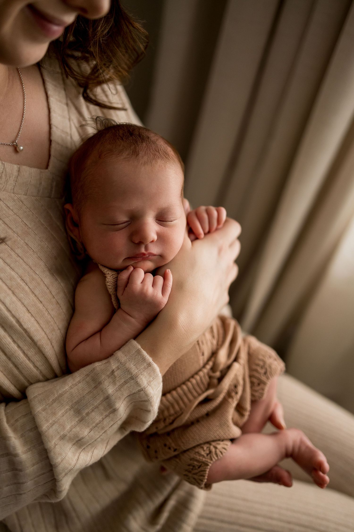 A sleeping baby swaddled in warm neutral tones rests peacefully in a cozy environment.
