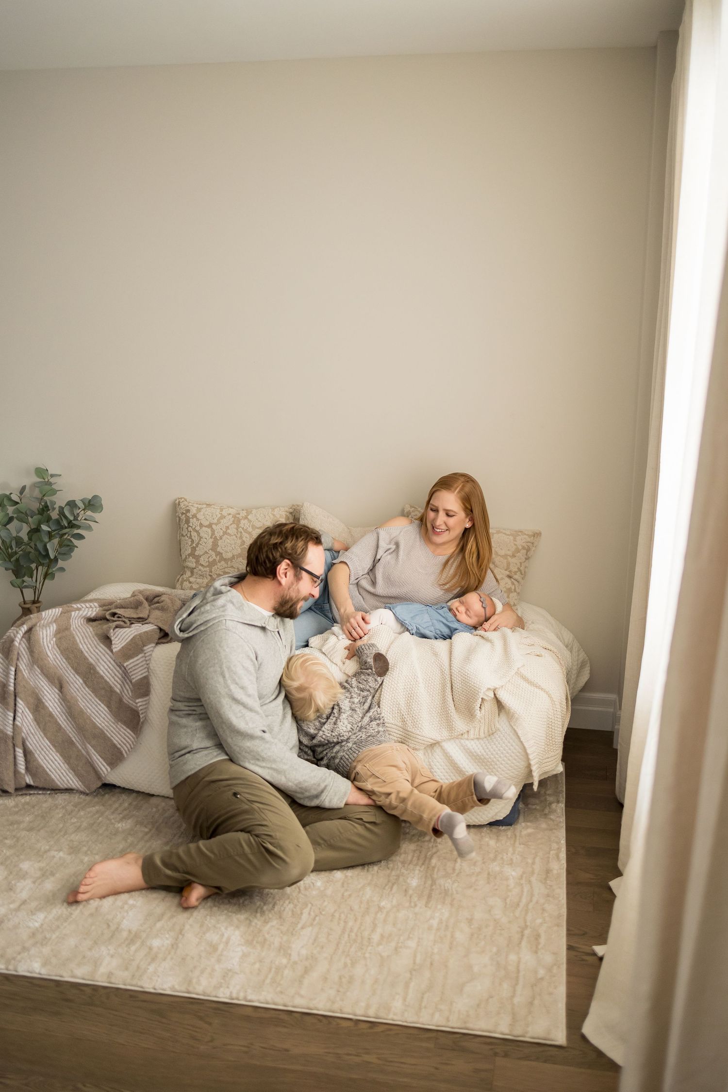 A couple and their dog share tender moments while relaxing on a cozy carpet in a minimalist room.