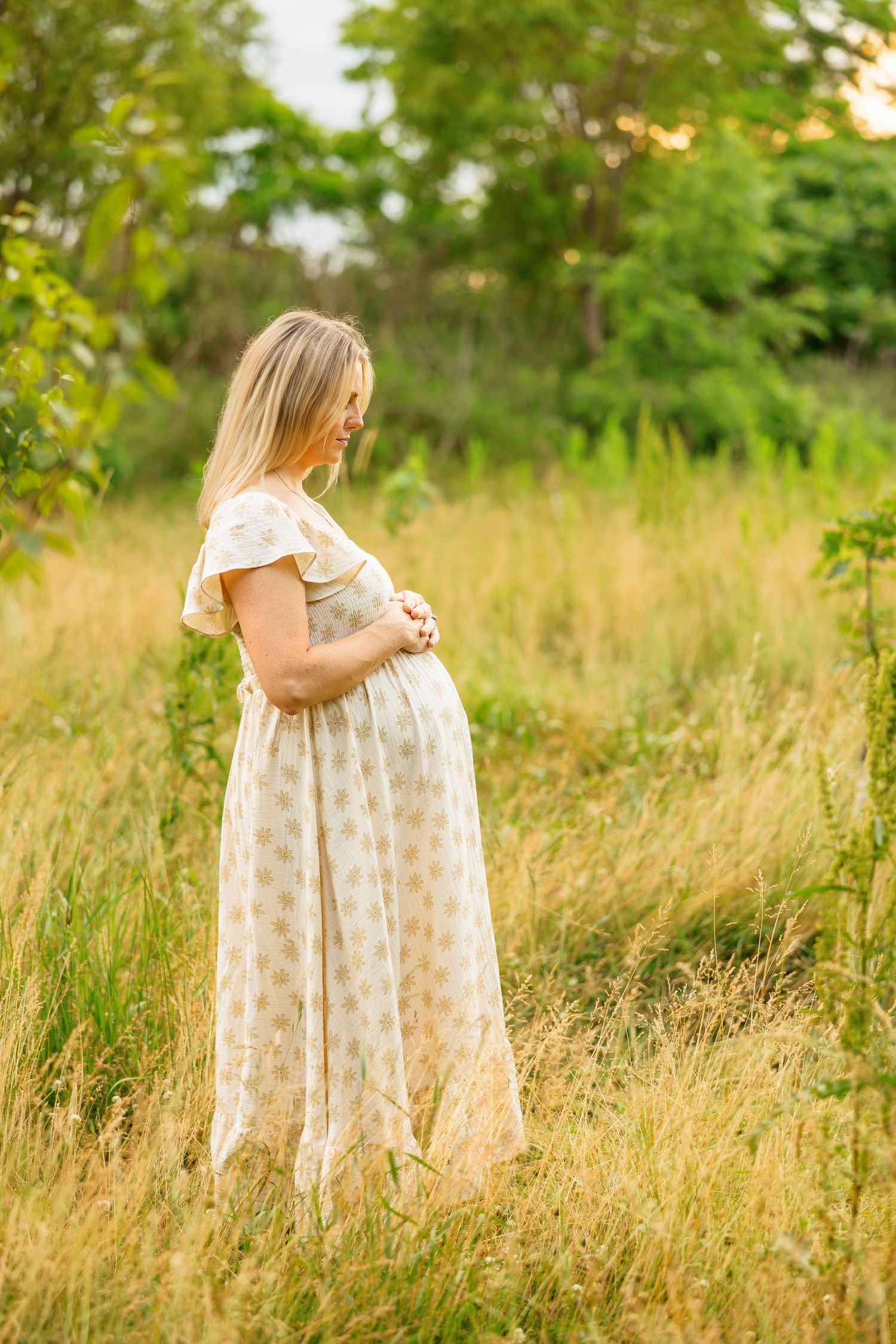 A maternity session in a golden field with flowing dress and natural evening light.