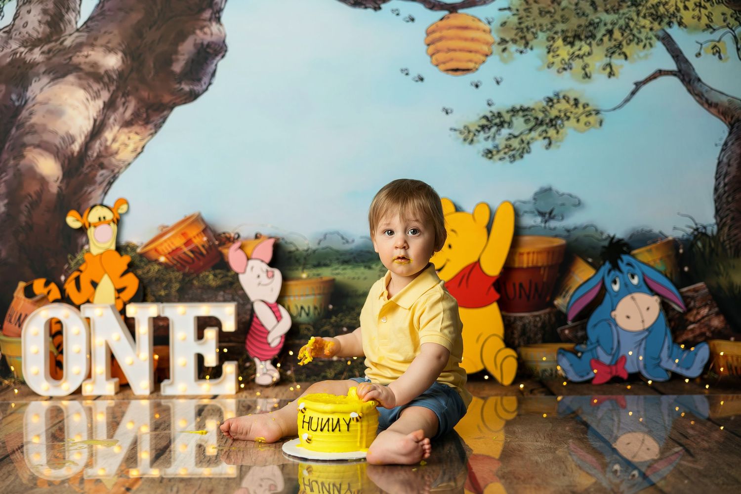 First birthday photoshoot with Winnie the Pooh themed backdrop and decorations.