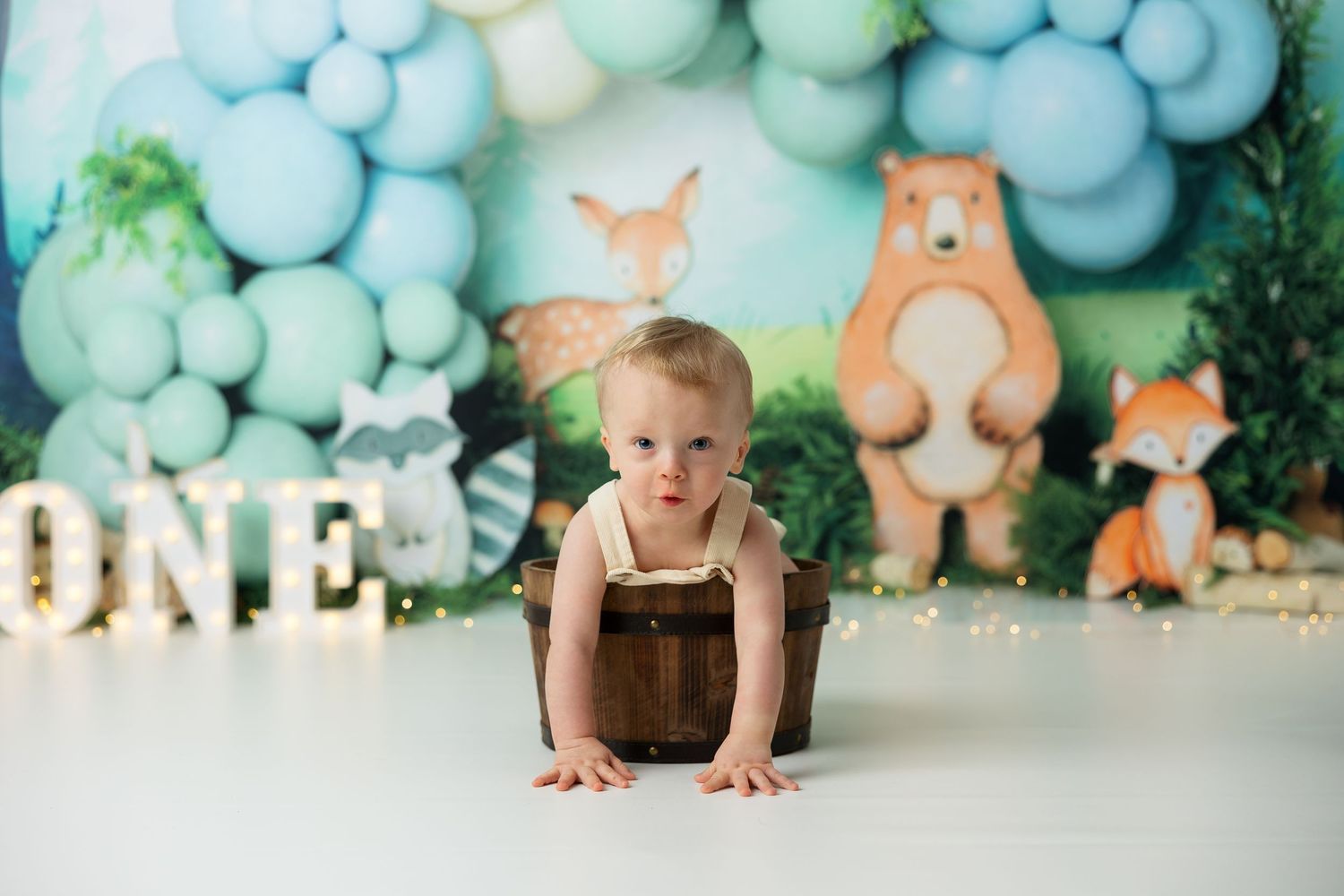 Woodland forest theme party setup with blue and mint balloon garland and fox decorations.