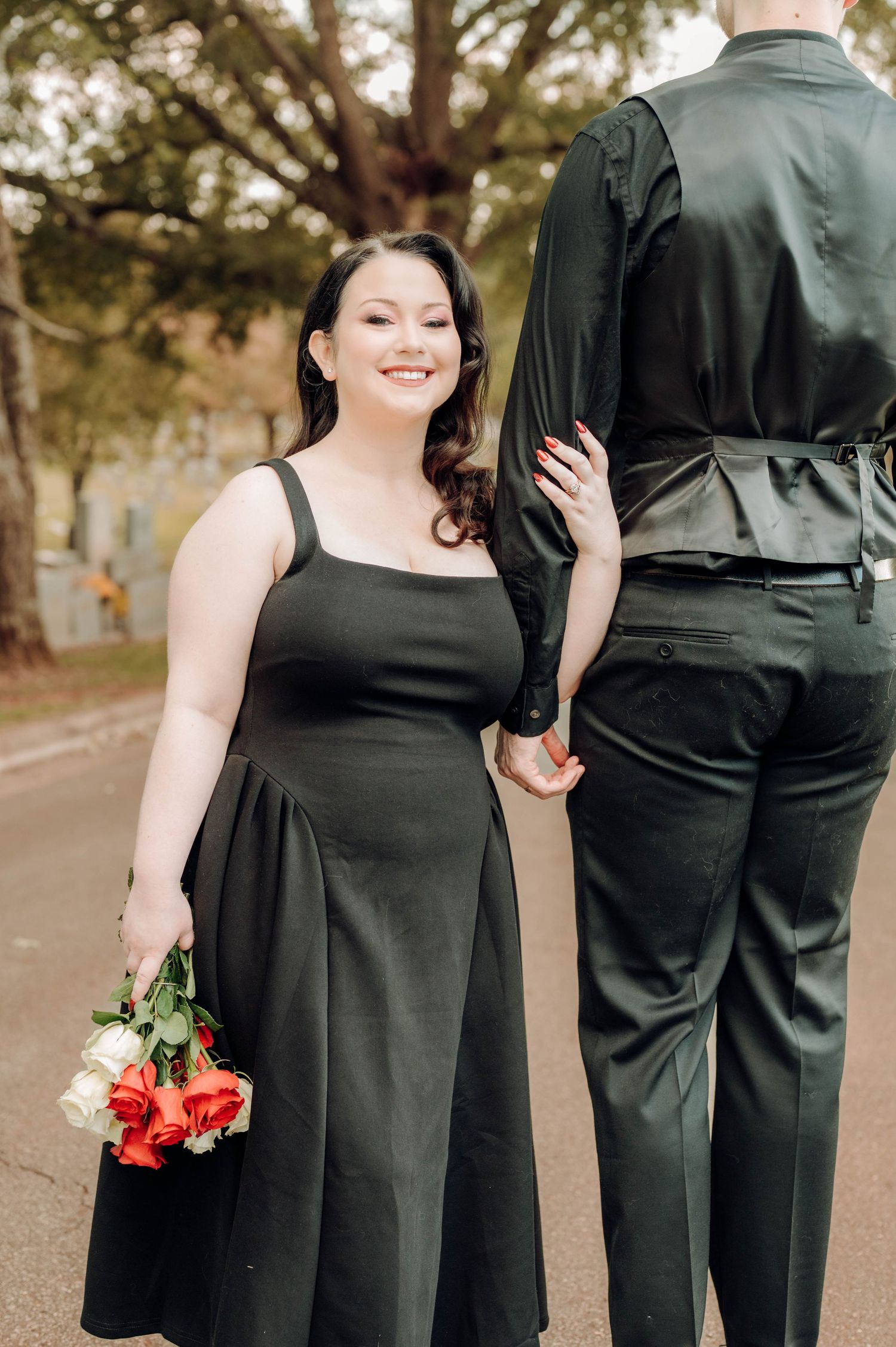 A romantic wedding photo series showing a couple in black formal attire holding hands and posing together outdoors.