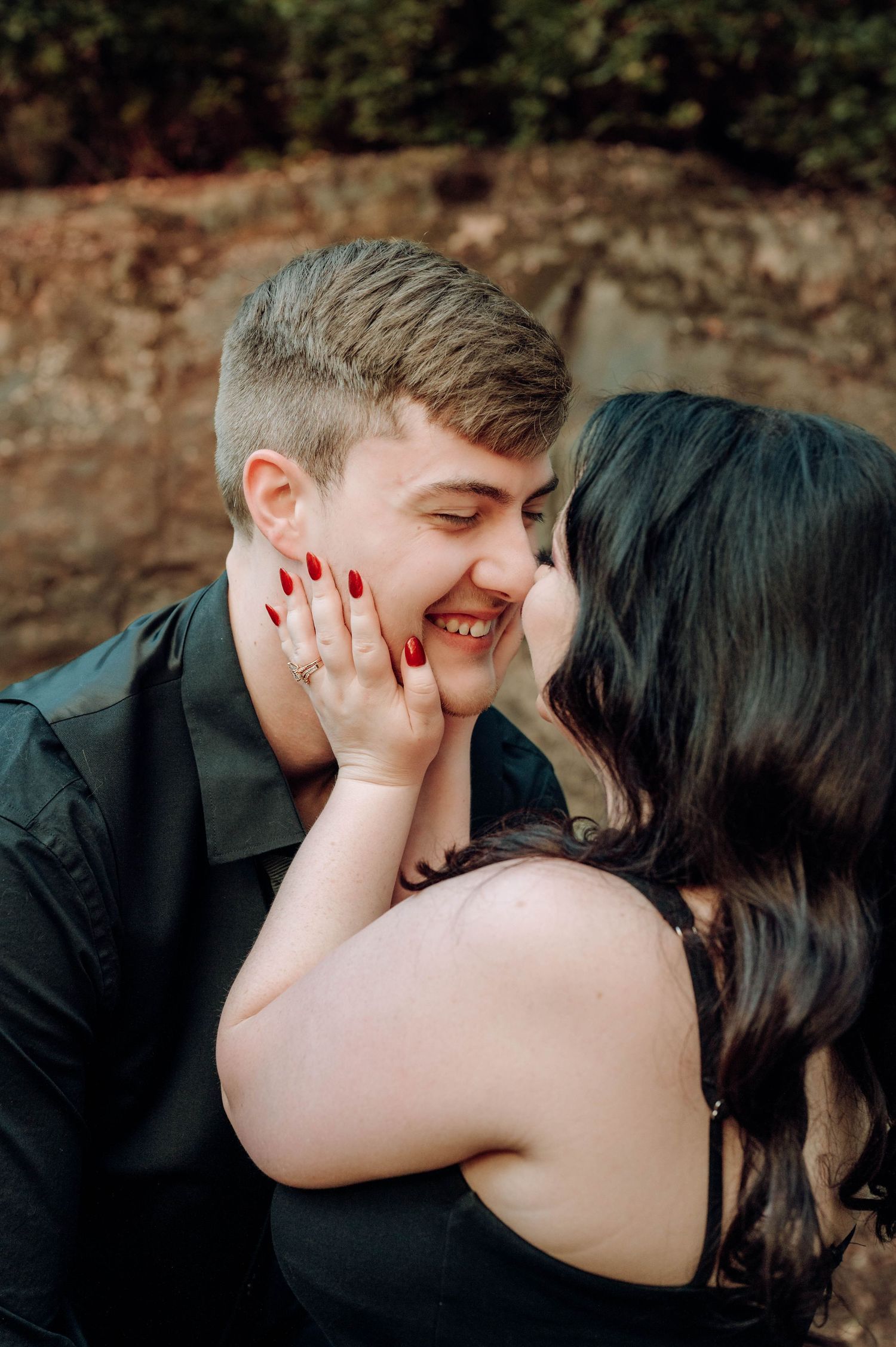 A romantic sequence of candid moments showing a couple sharing laughter and tender embraces against a stone wall background.