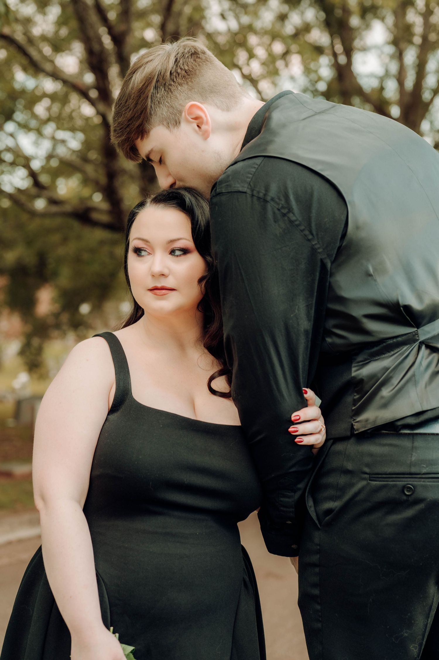 A romantic couple in black attire share tender moments in a series of intimate outdoor portrait photographs.