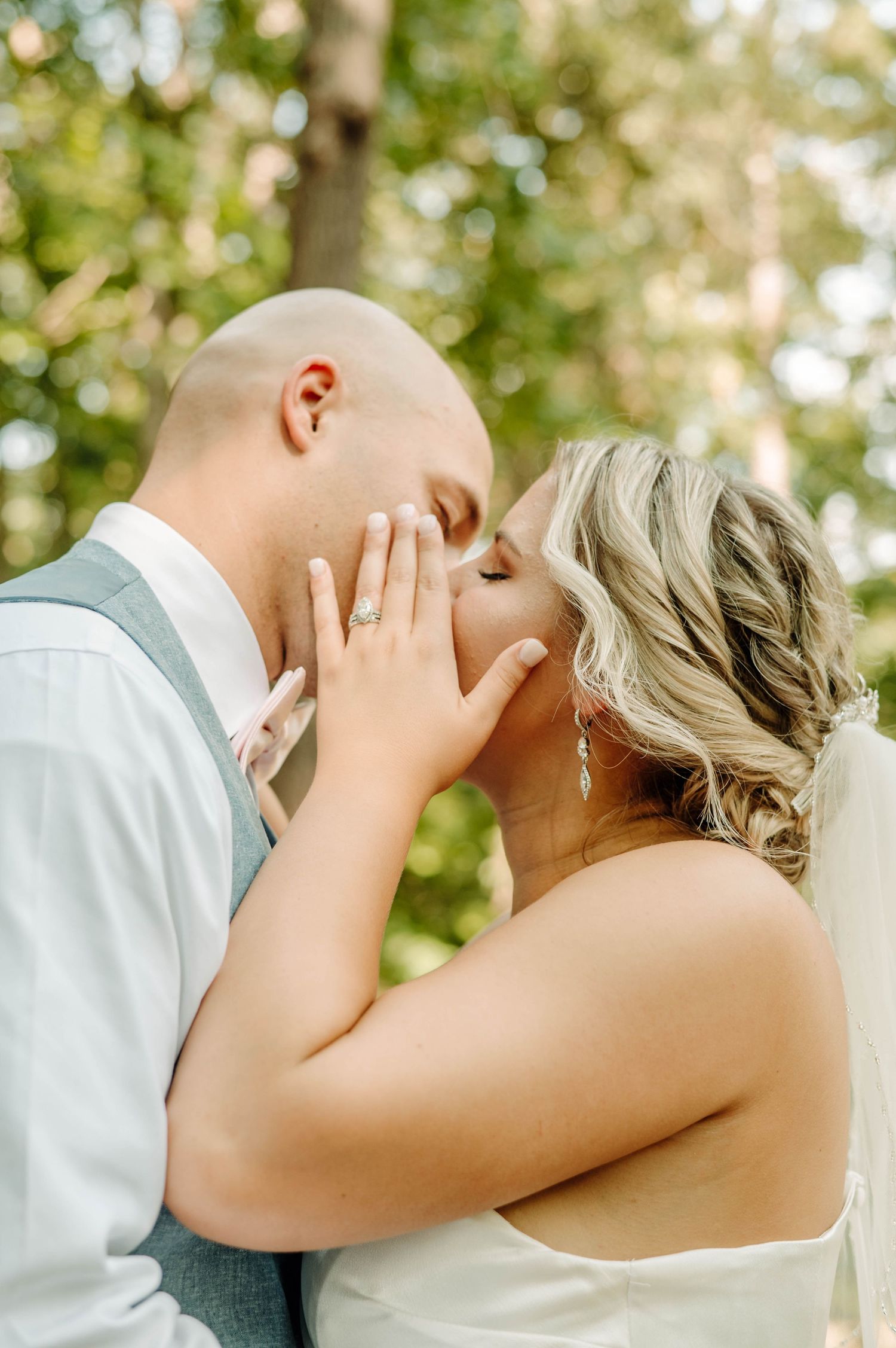 Romantic outdoor wedding photo of couple sharing intimate moment in natural lighting.