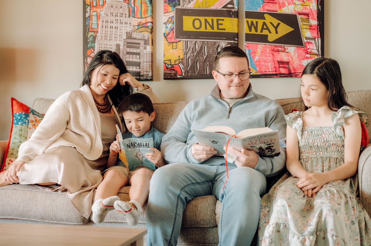 Family relaxing on couch with colorful urban artwork and street signs on wall behind them.