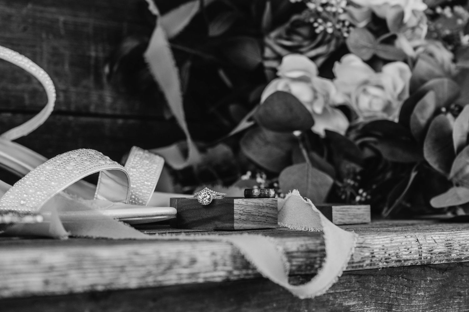 Wedding details with white ribbon and ring in black and white photography.