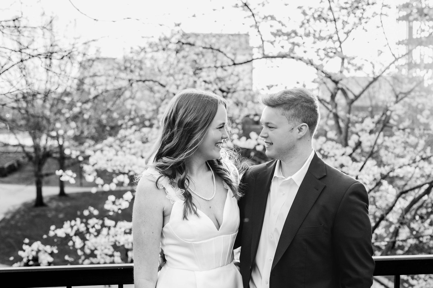 A romantic black and white portrait of a couple amid blooming cherry blossoms.