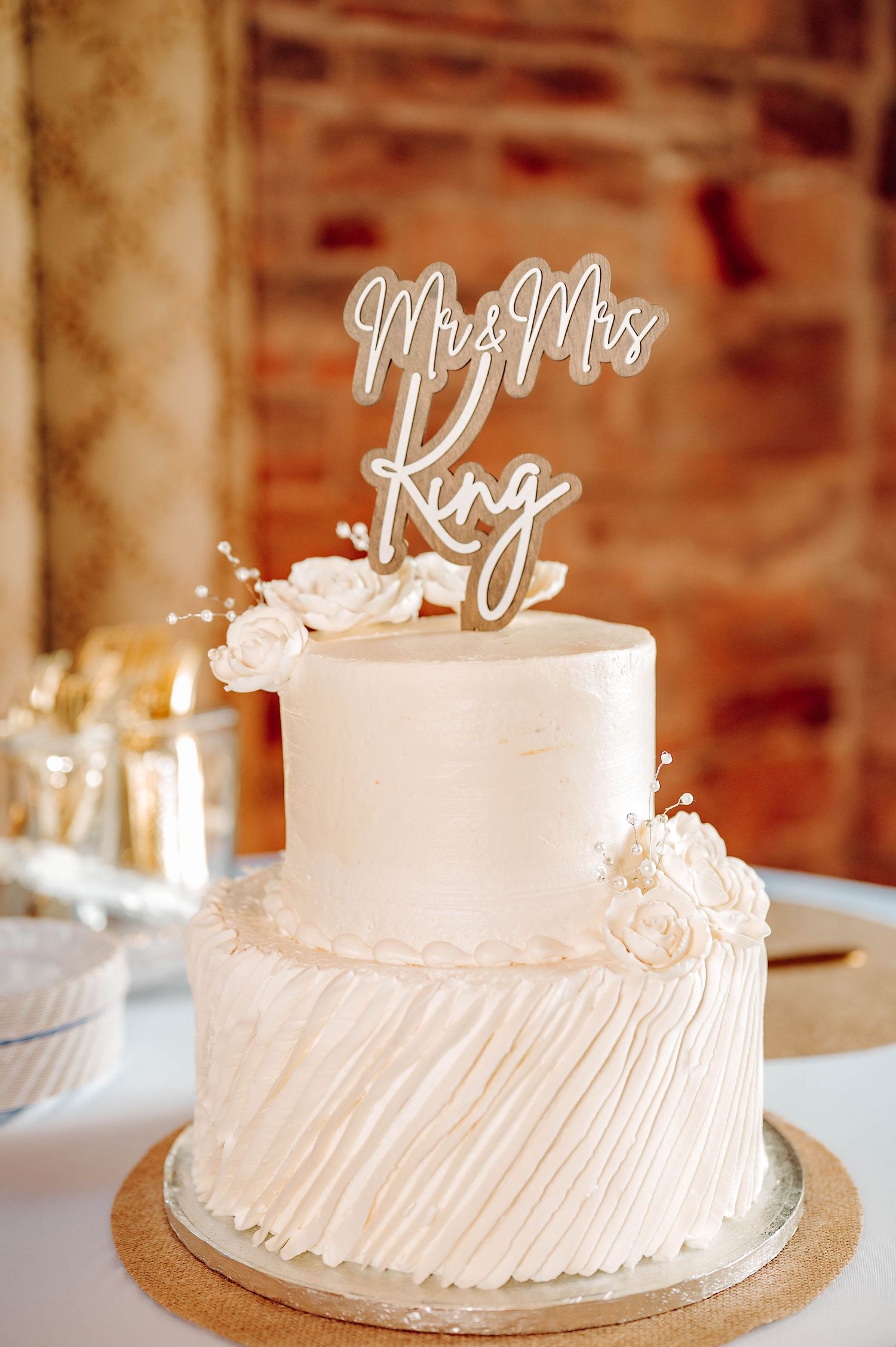 A series of elegant white wedding cakes with delicate frosting details and decorative toppers on display.