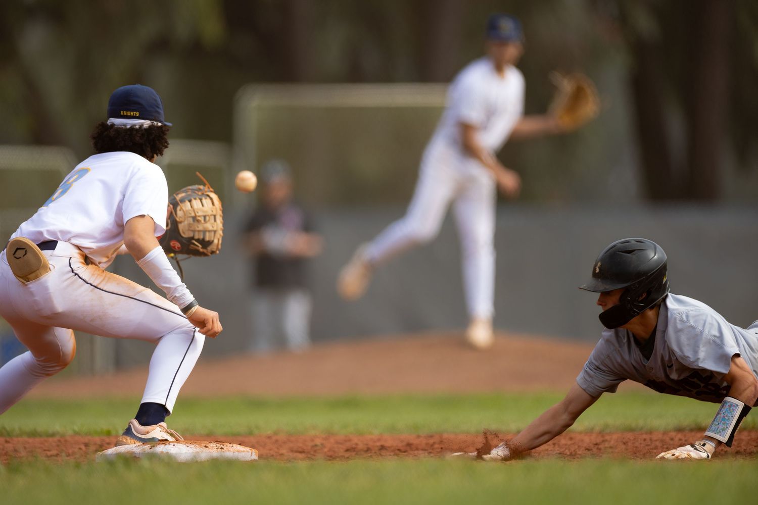 Baseball players execute sliding plays and defensive moves during a competitive game.