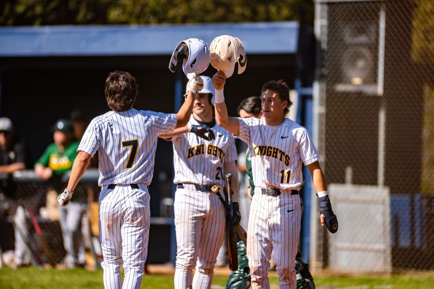 Baseball players in pinstripe uniforms gather on the field during a sunny day game.