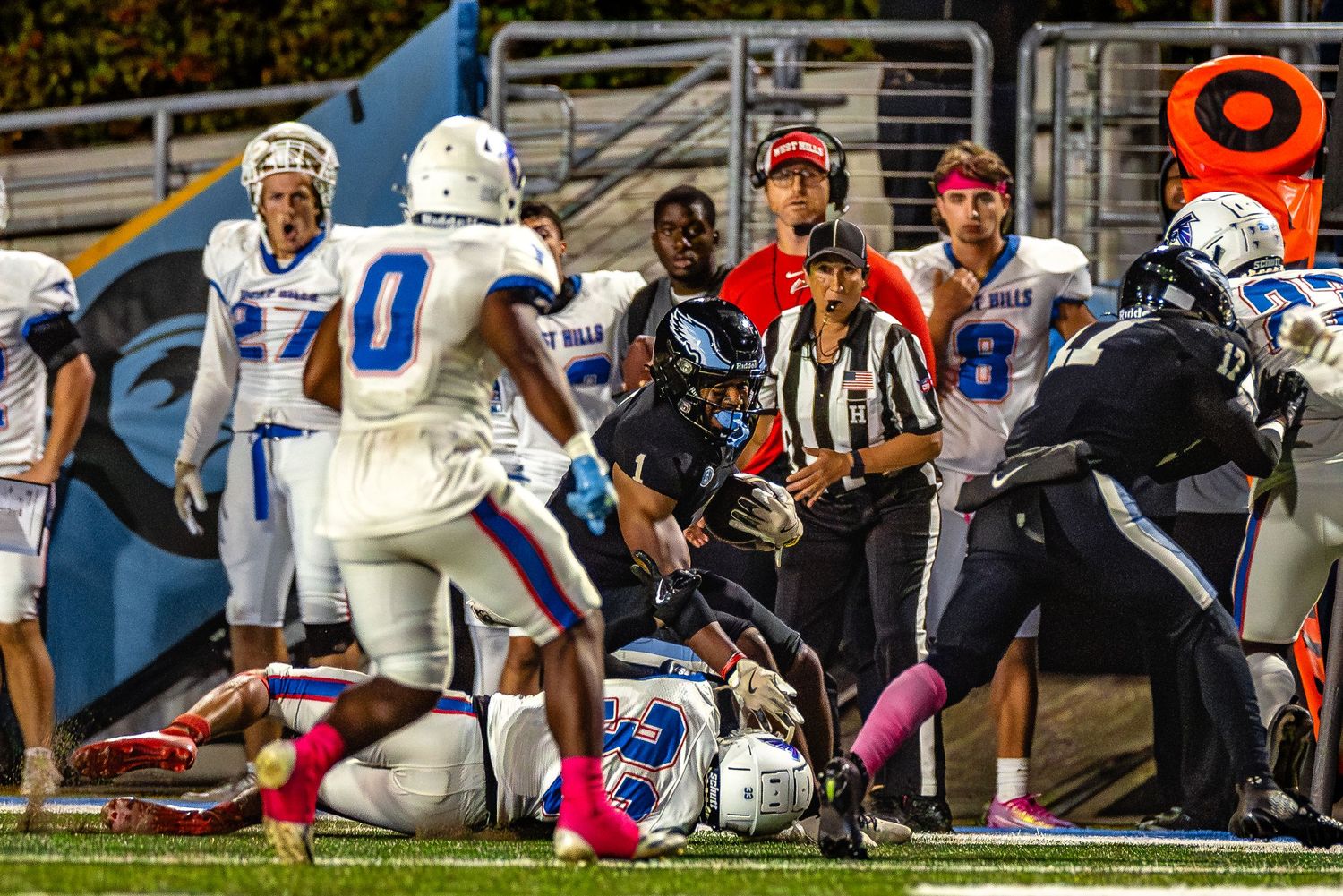 Multiple football players engage in a dynamic play during a collegiate match on the field.