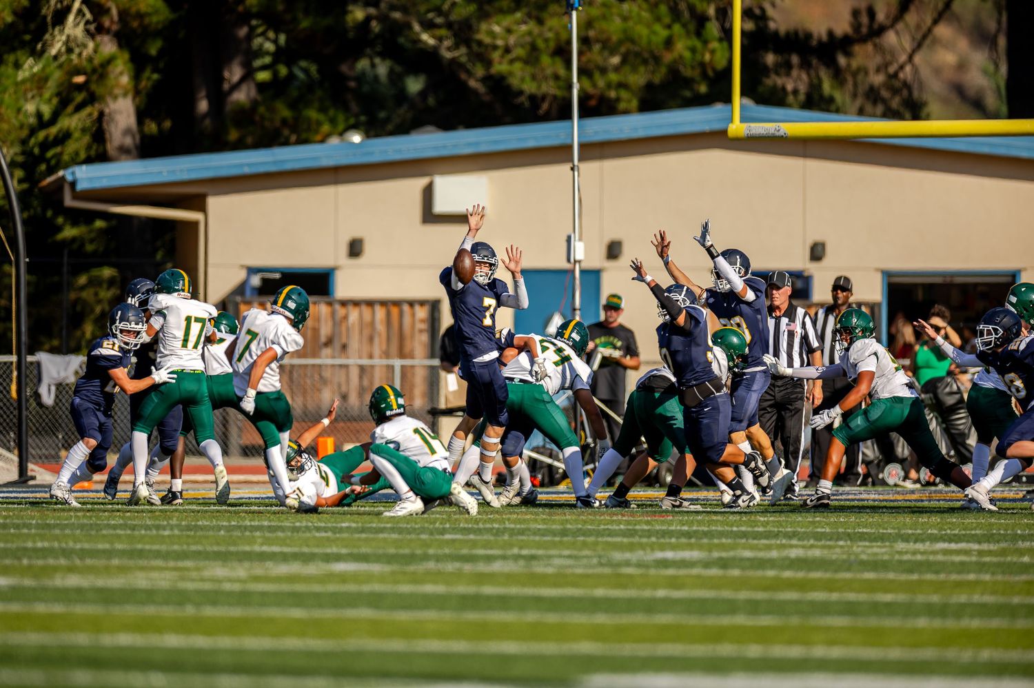 A sequence of football players engaged in tackles and plays on a sunny field during a match.