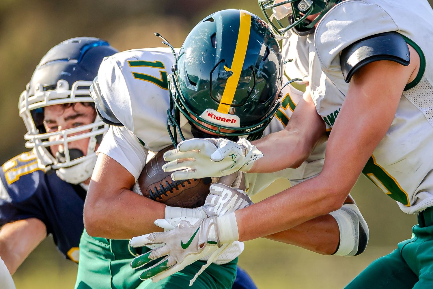 Football players collide during an intense tackle attempt on the field during a competitive game.