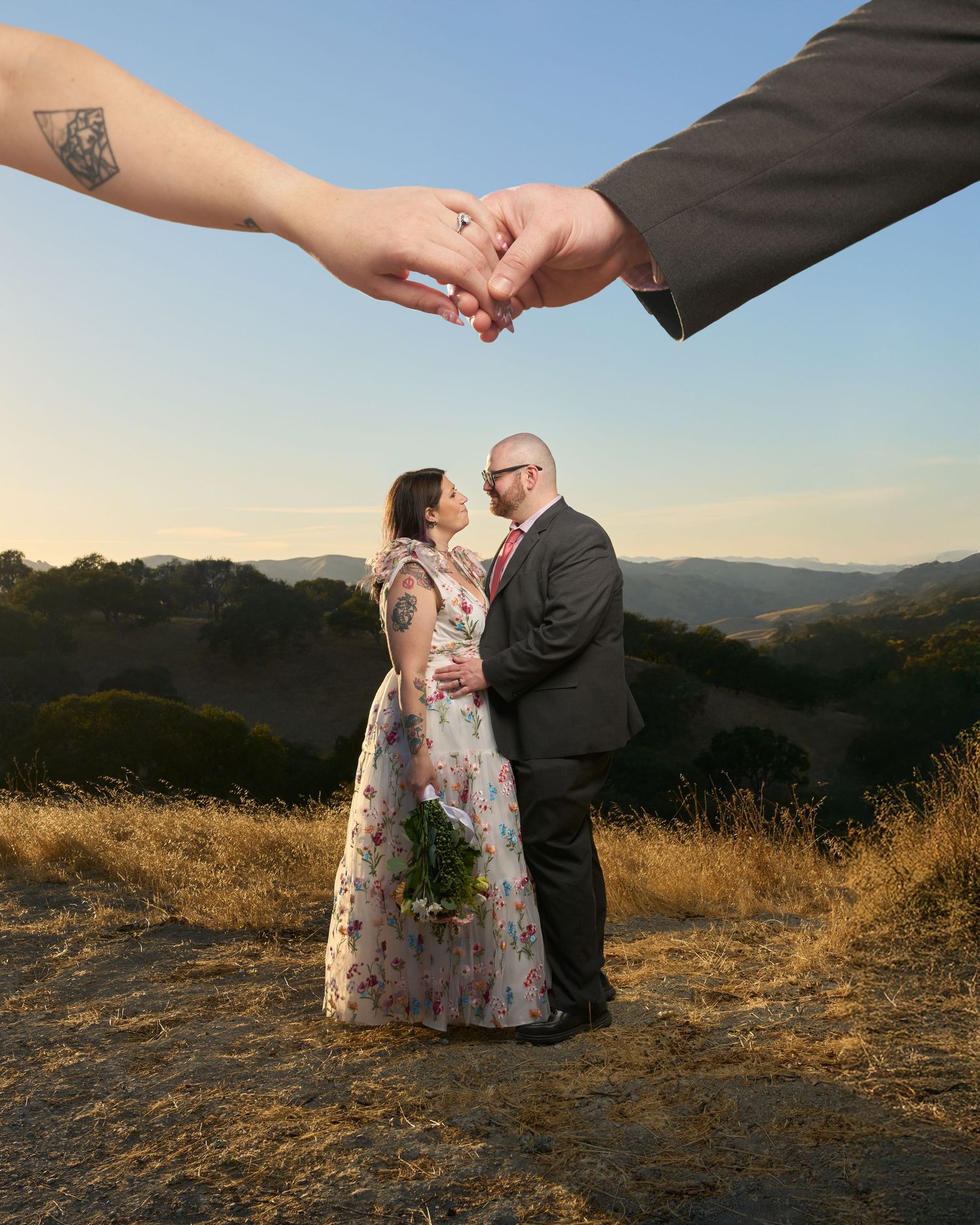 A bride and groom smiling at each other with their hands above them.
