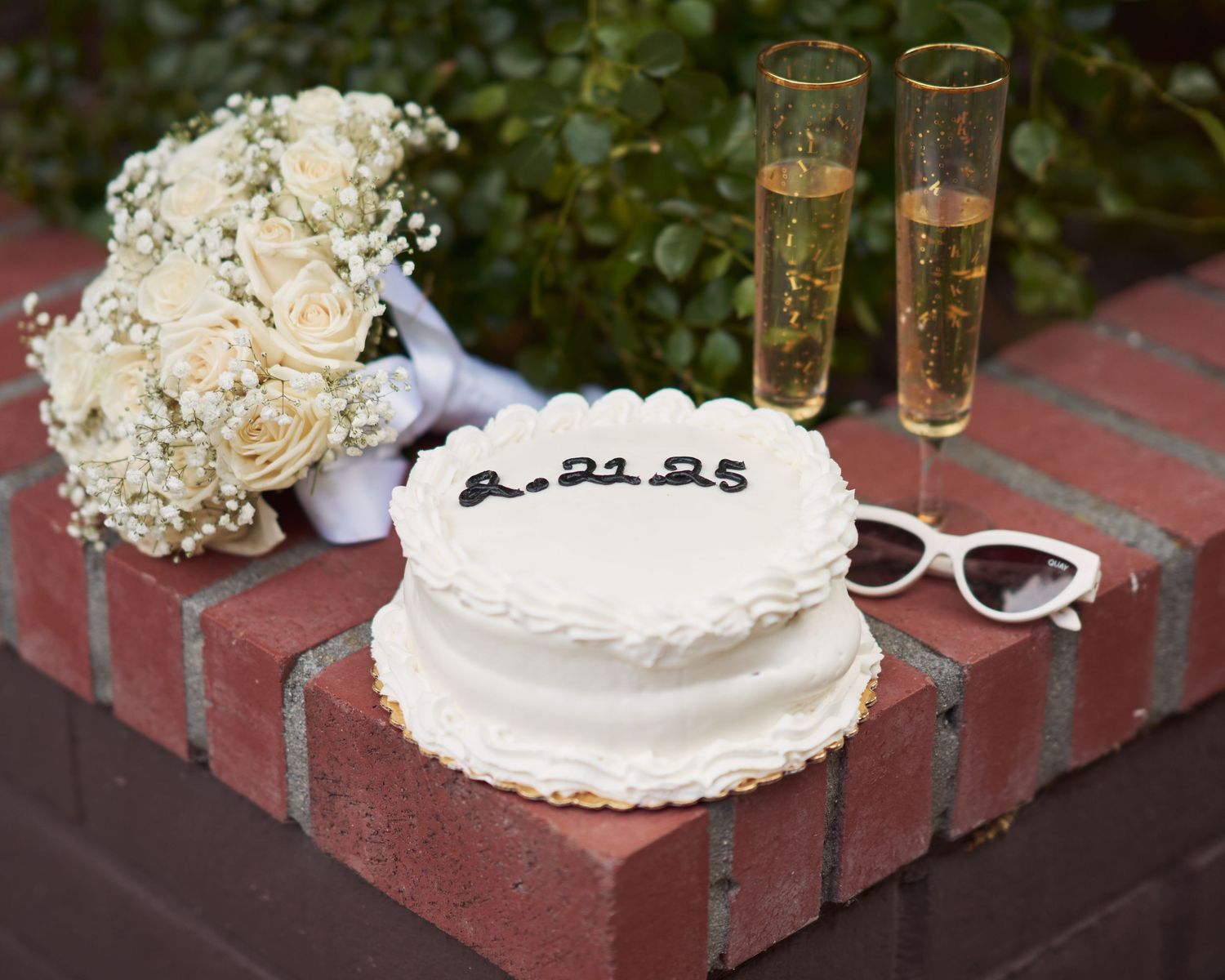 A cake, sunglasses, and flower bouquet for a wedding announcement.