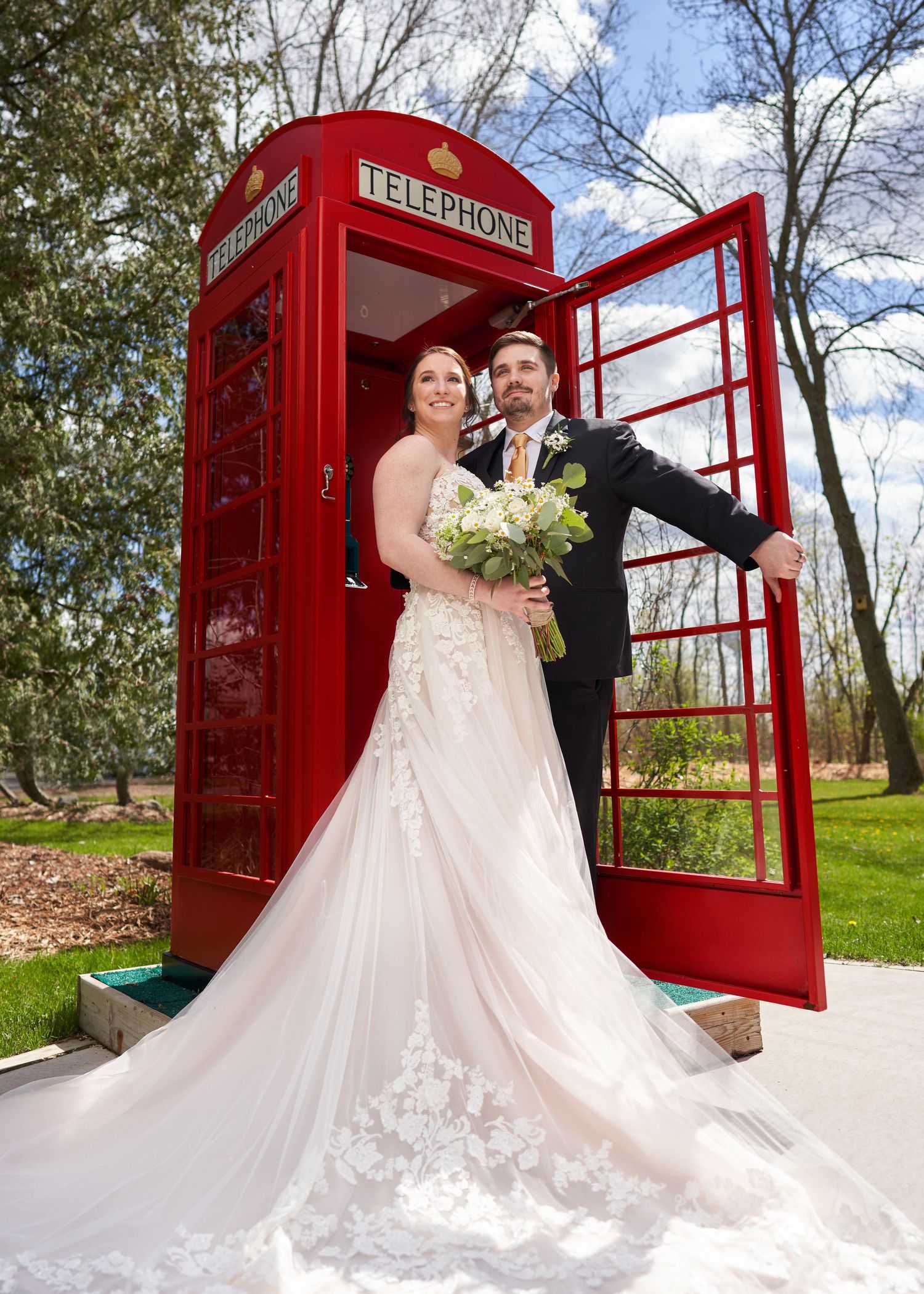 A couple standing in front of a telephone booth.