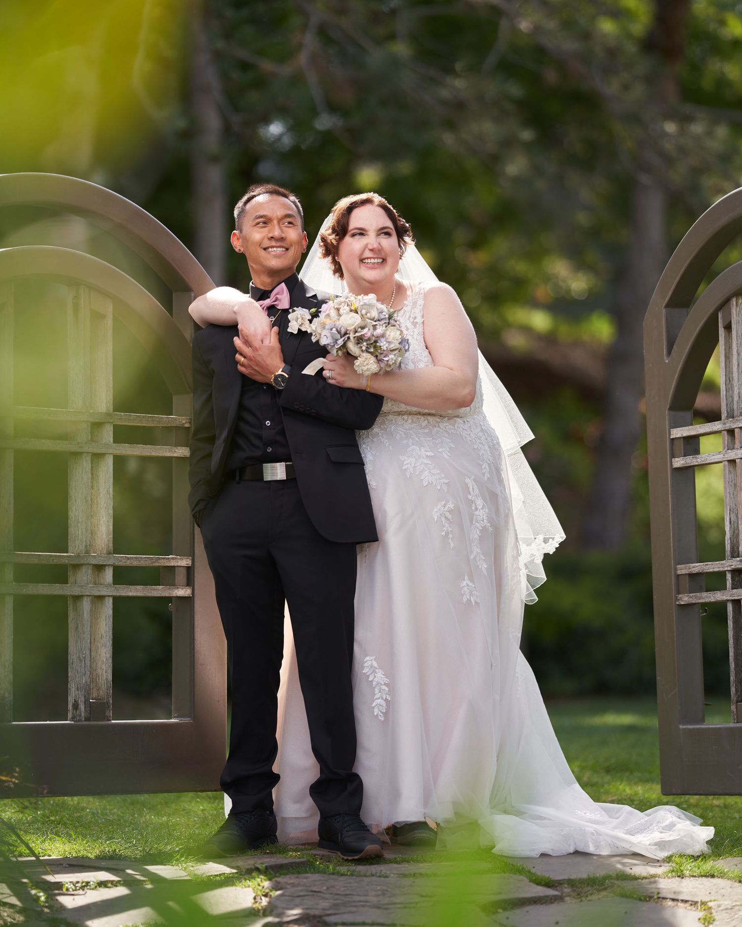 A bride and groom smiling into the distance on their wedding day in front of a gate.