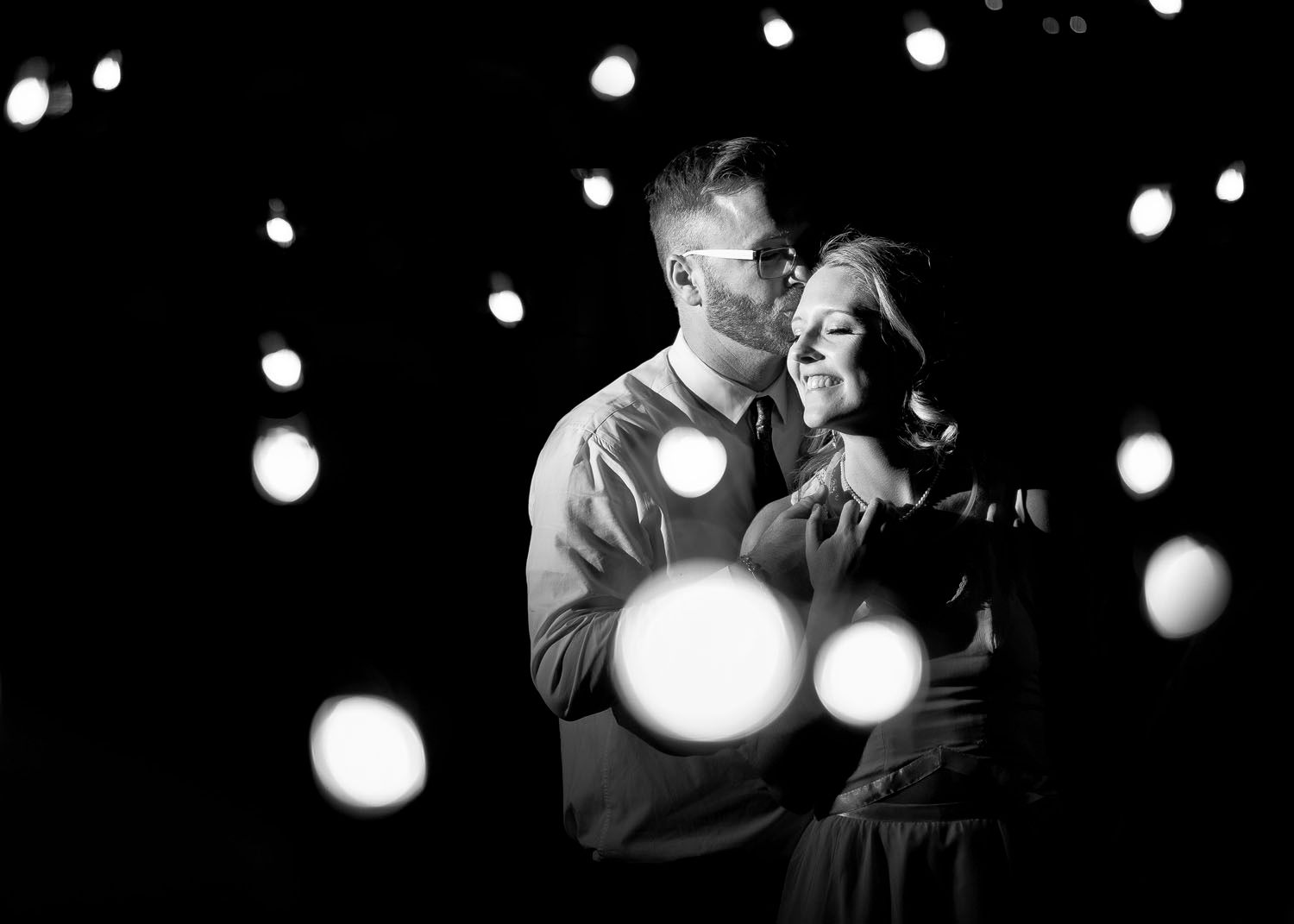 Black and white photo of groom kissing bride on head captured by Full Flare Photography