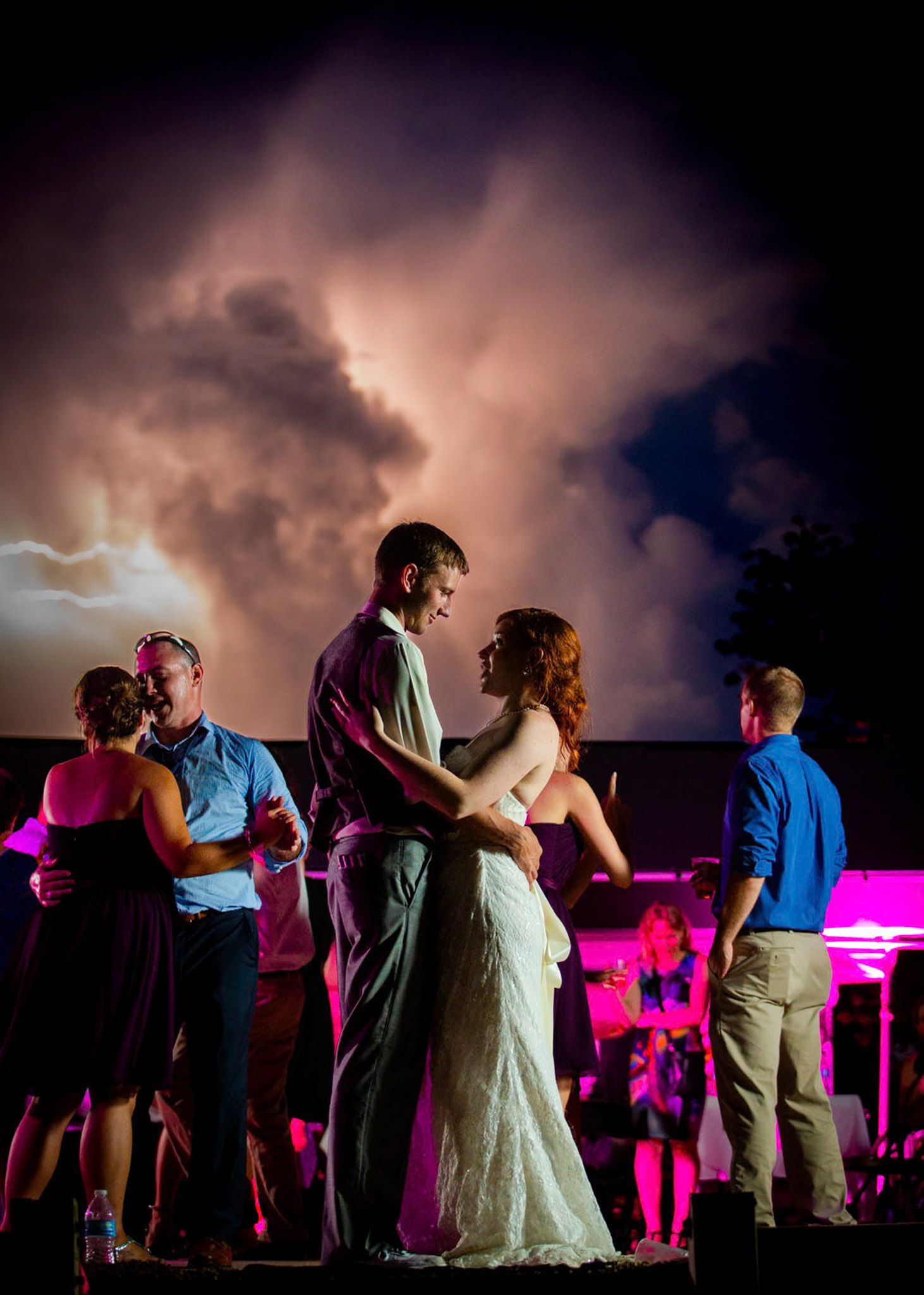 Married couple at wedding with lightening in in the background captured by Full Flare Photography