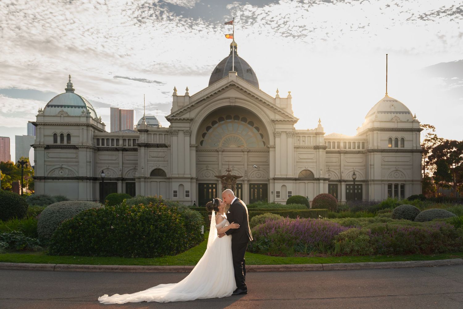 Bride and groom kissing in front of the Royal Exhibition Building Melbourne at sunset on their wedding day.