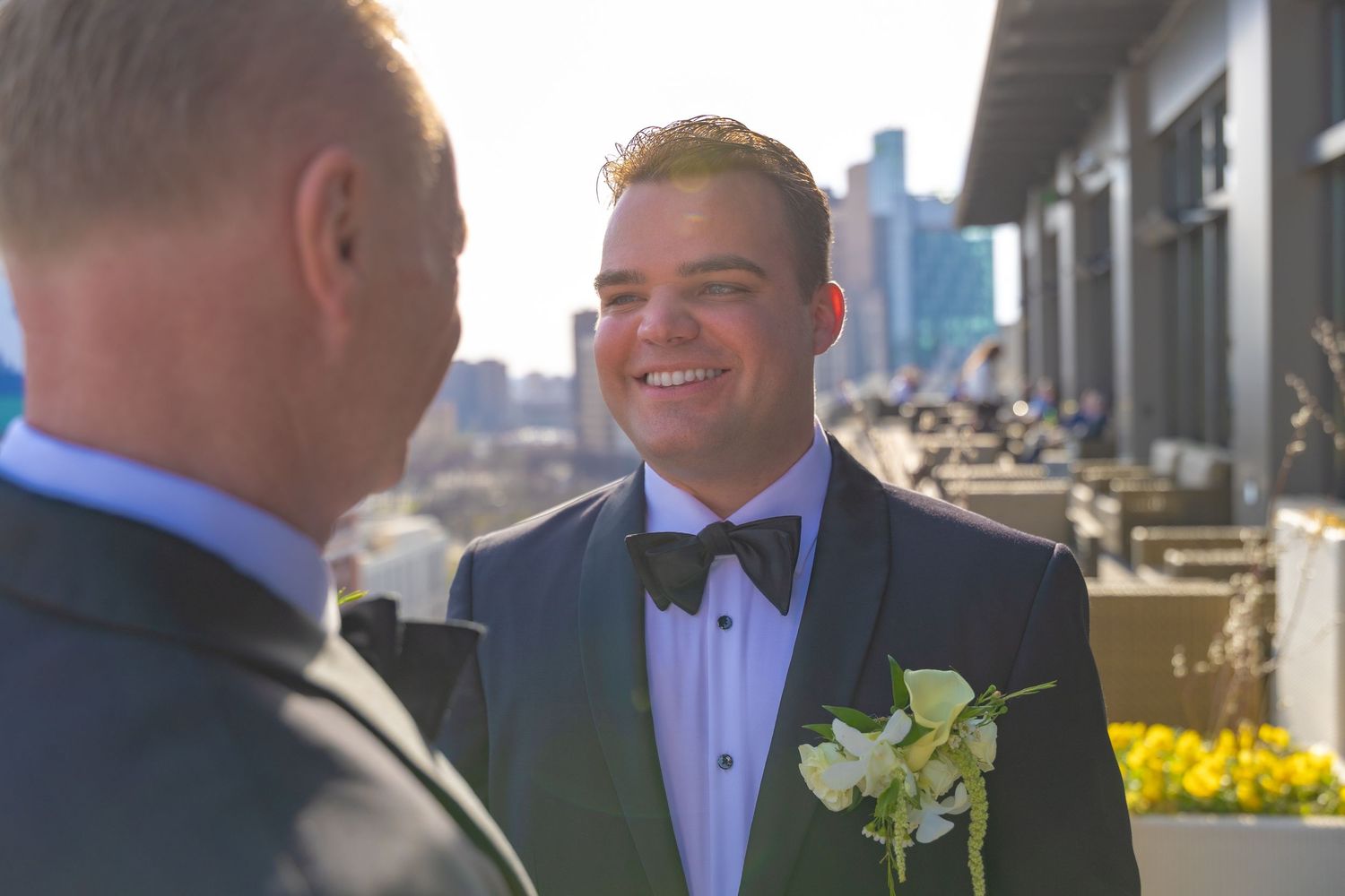 A couple shares a joyous moment on after their wedding ceremony at Detroit Athletic Club on a balcony patio overlooking downtown Detroit.