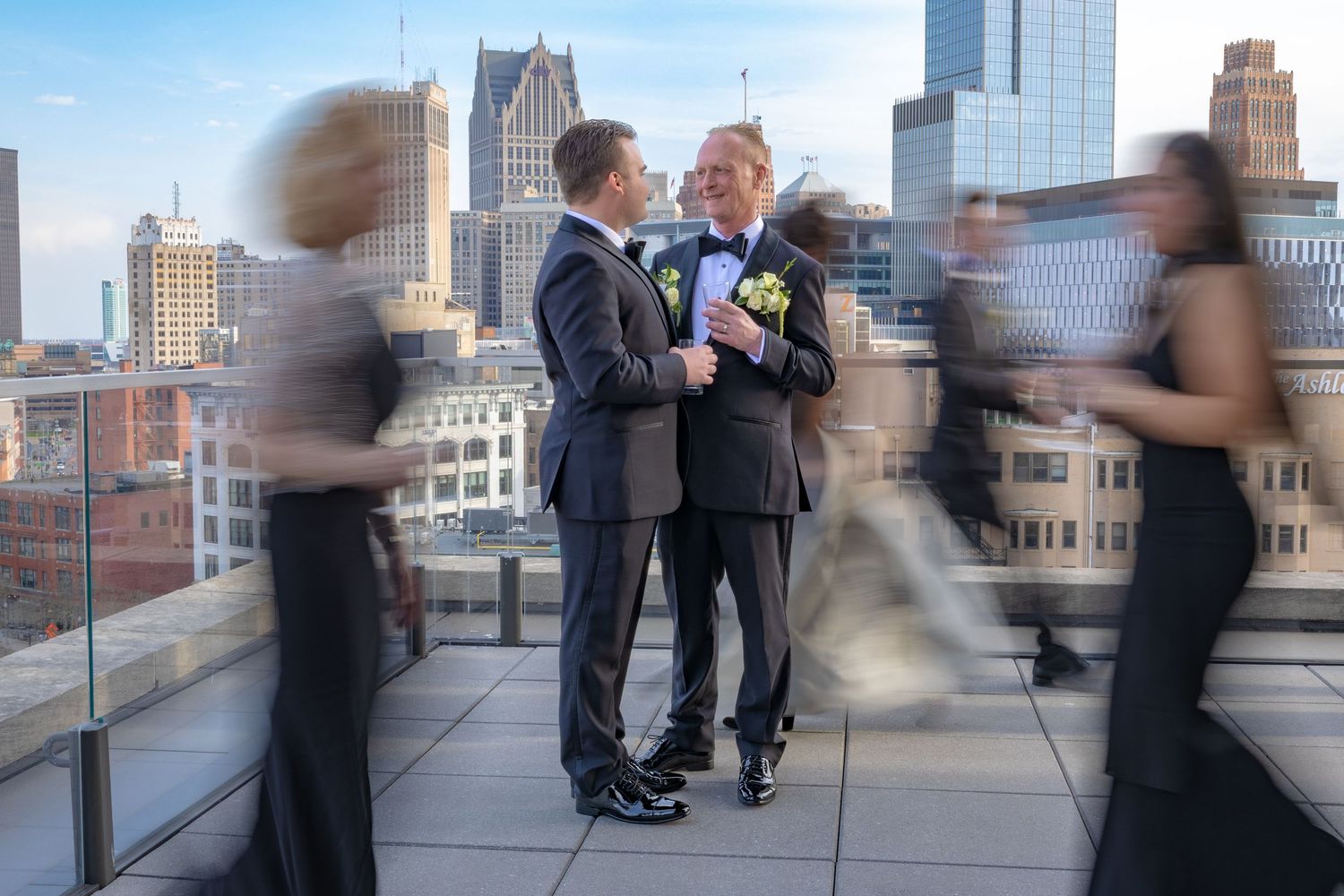 A couple poses for artistic wedding portraits atop the Detroit Athletic Club with motion blur, with the city skyline in the background.