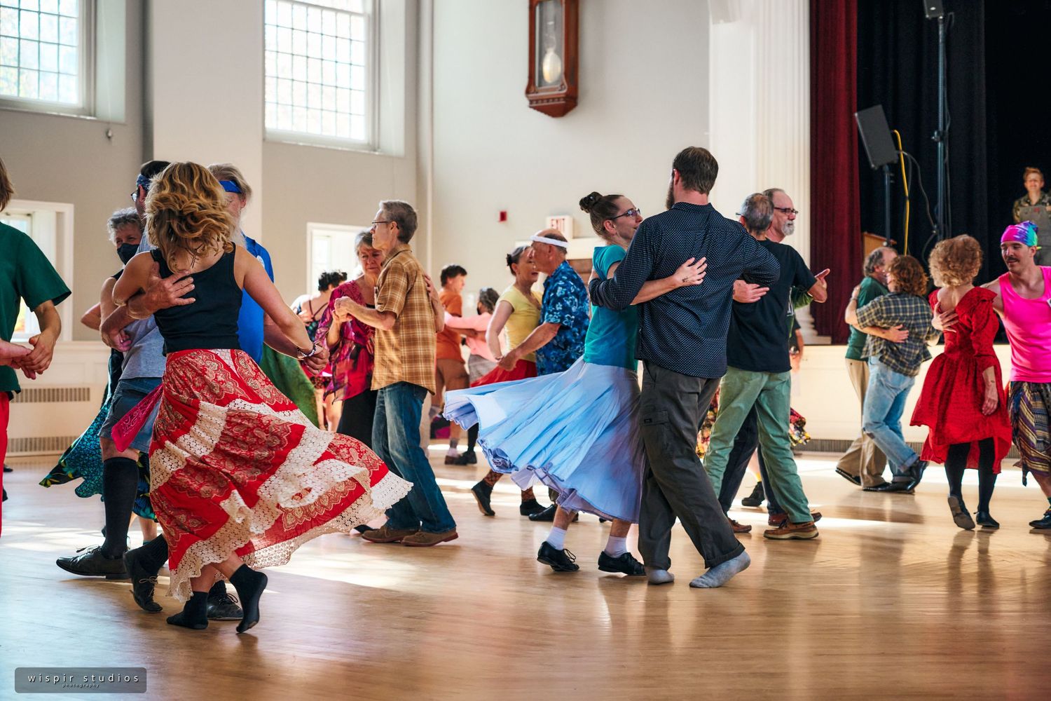 Group dance class in a bright studio with large windows and wooden floors.