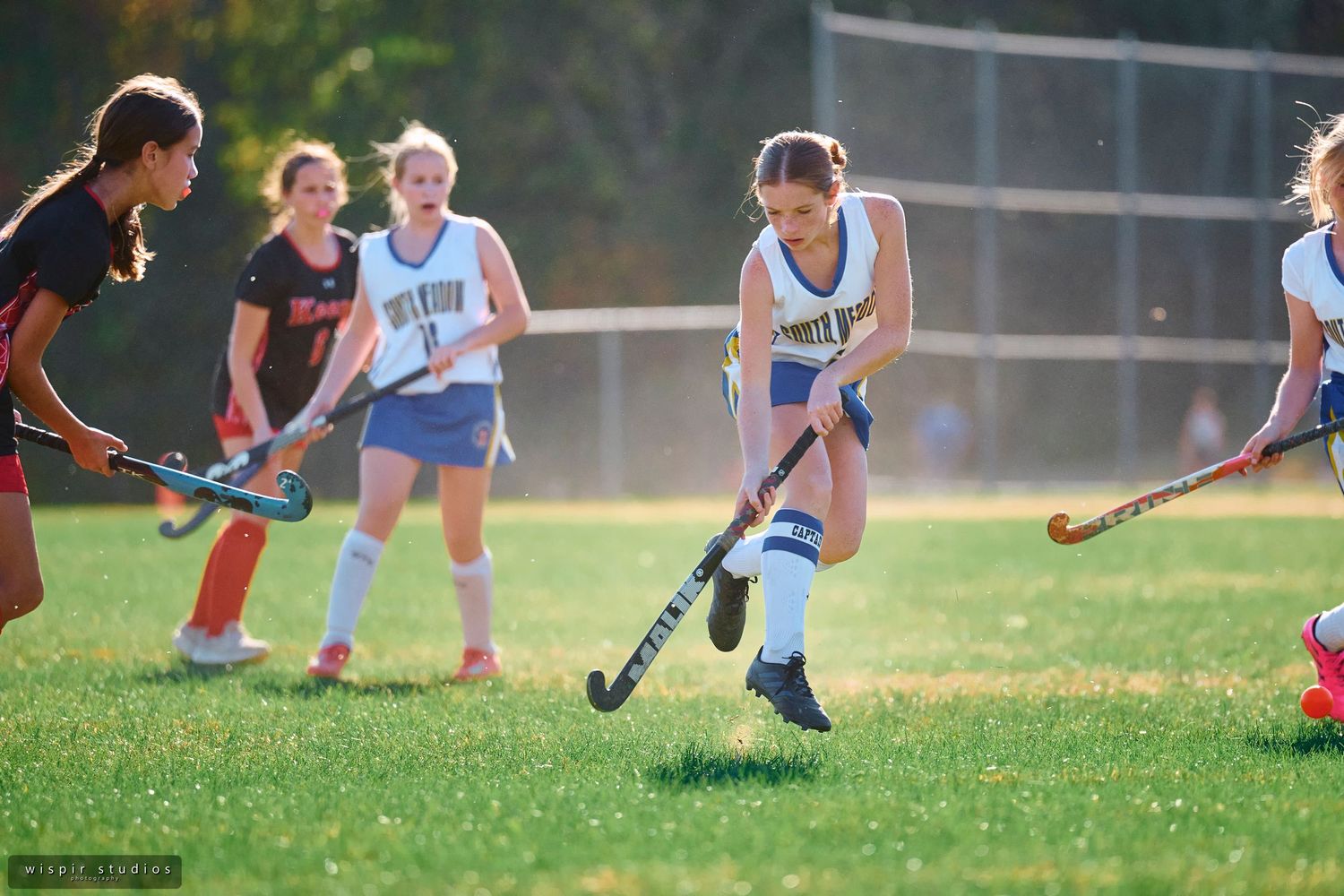 Field hockey players compete for possession of the ball during an intense match on a sunny afternoon.