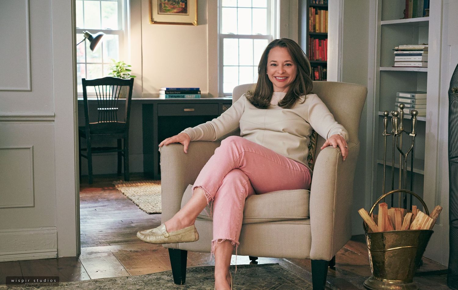 Person relaxes on a cozy grey couch in a bright living room with natural lighting and hardwood floors.