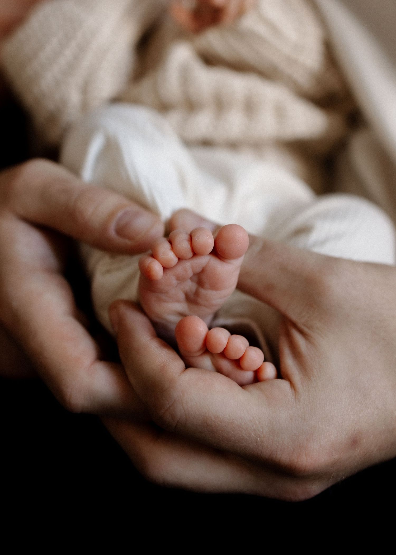Close-up of tiny baby feet cradled in gentle hands.