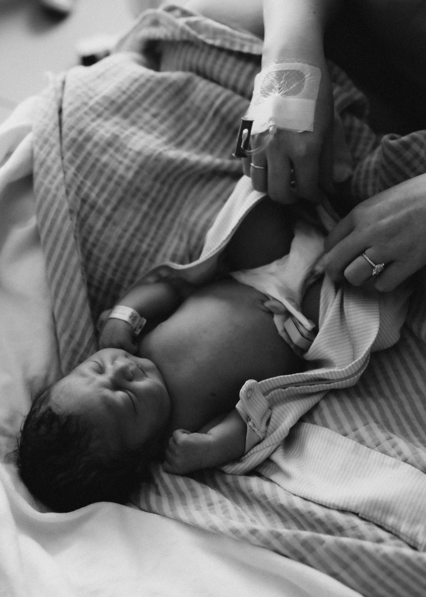 Newborn baby receiving medical care with visible hospital bracelet and blanket.