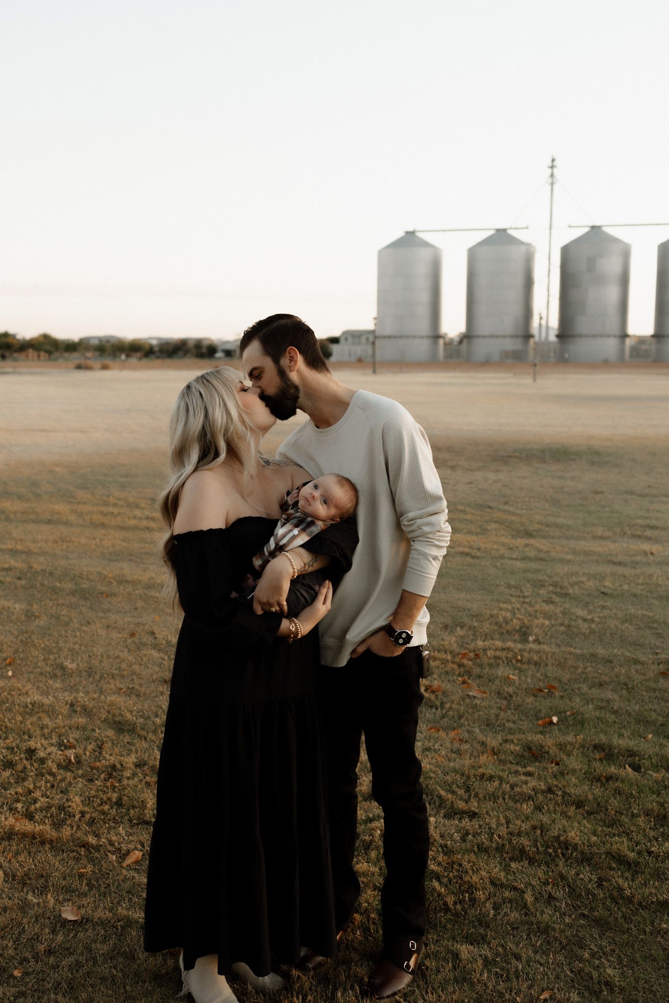 Family portrait with grain silos in background during golden hour.