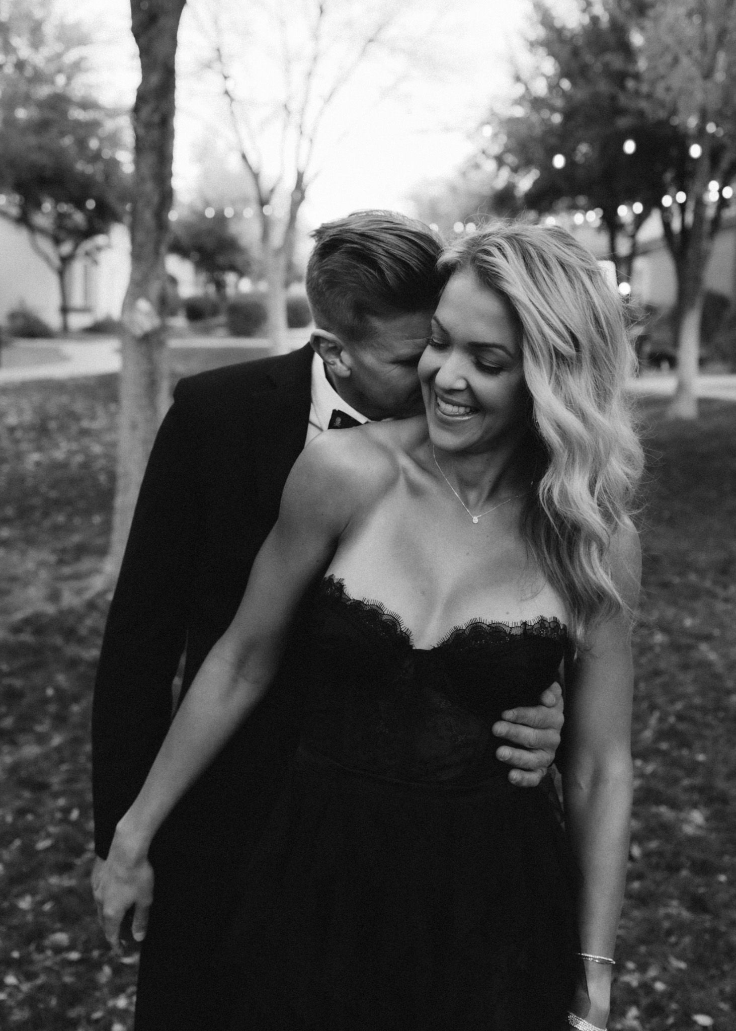 Elegant couple sharing a romantic moment outdoors in formal attire at dusk.