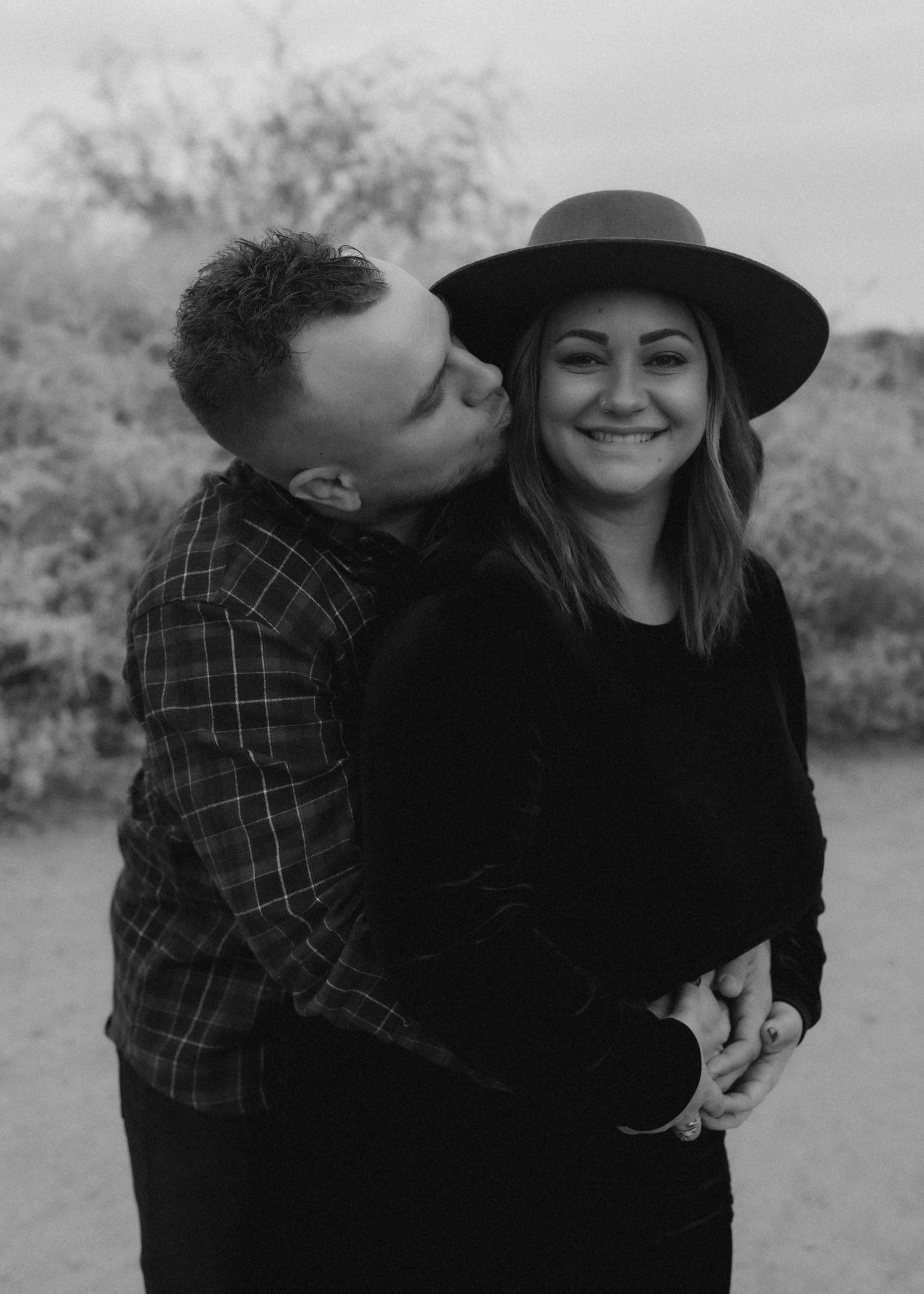 Black and white portrait of couple sharing affectionate moment outdoors.