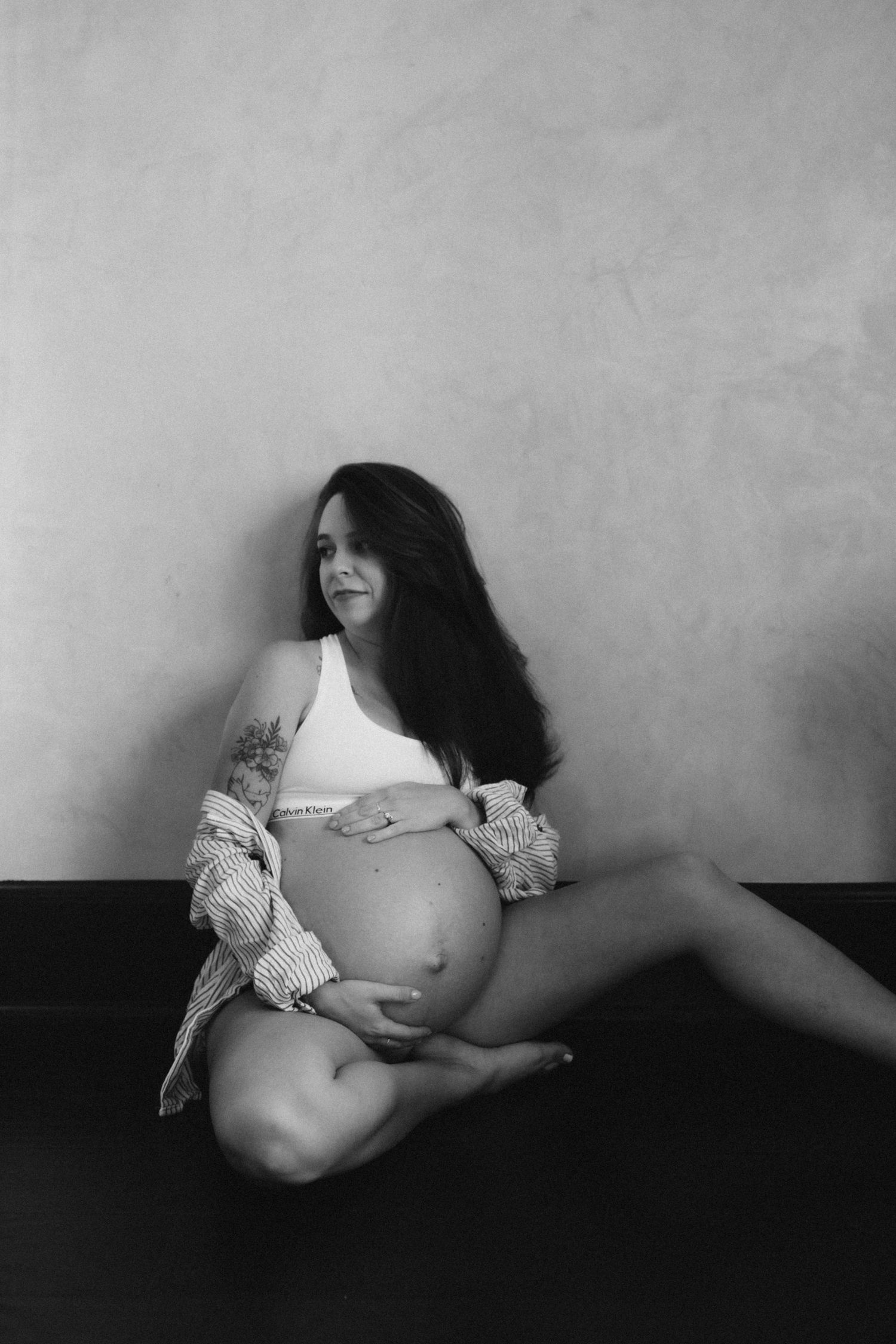 Black and white maternity portrait of expectant mother in casual white top.