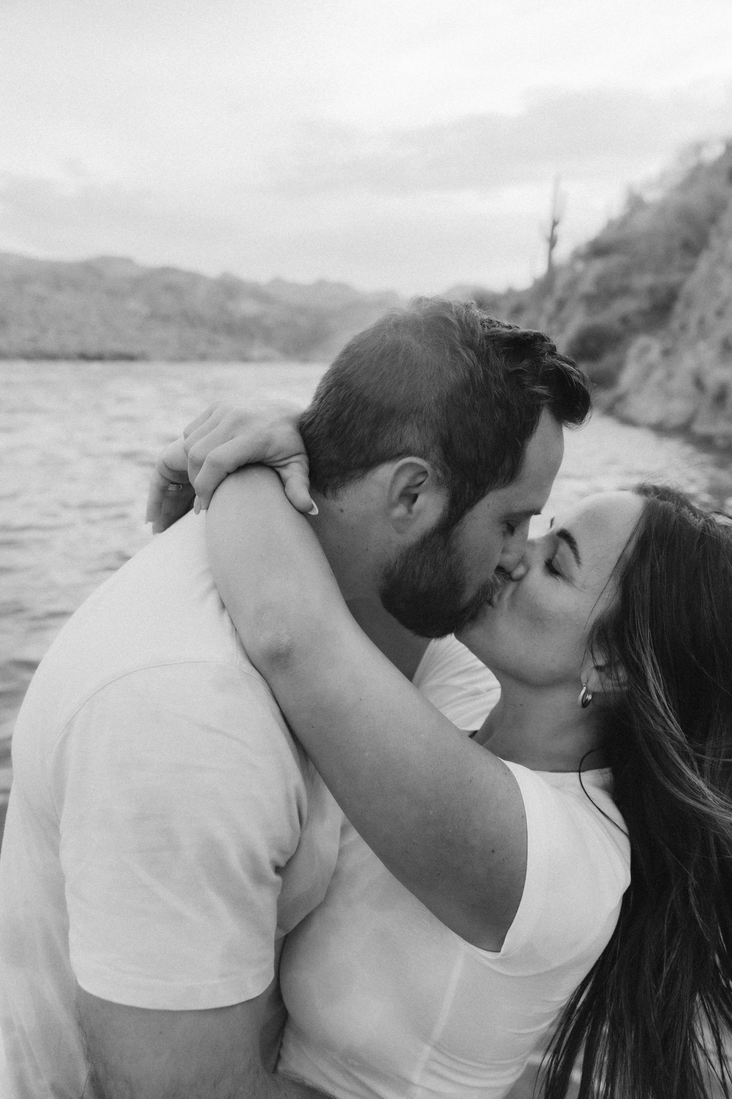 A romantic sequence of black and white photos showing a couple sharing intimate kisses by the ocean.