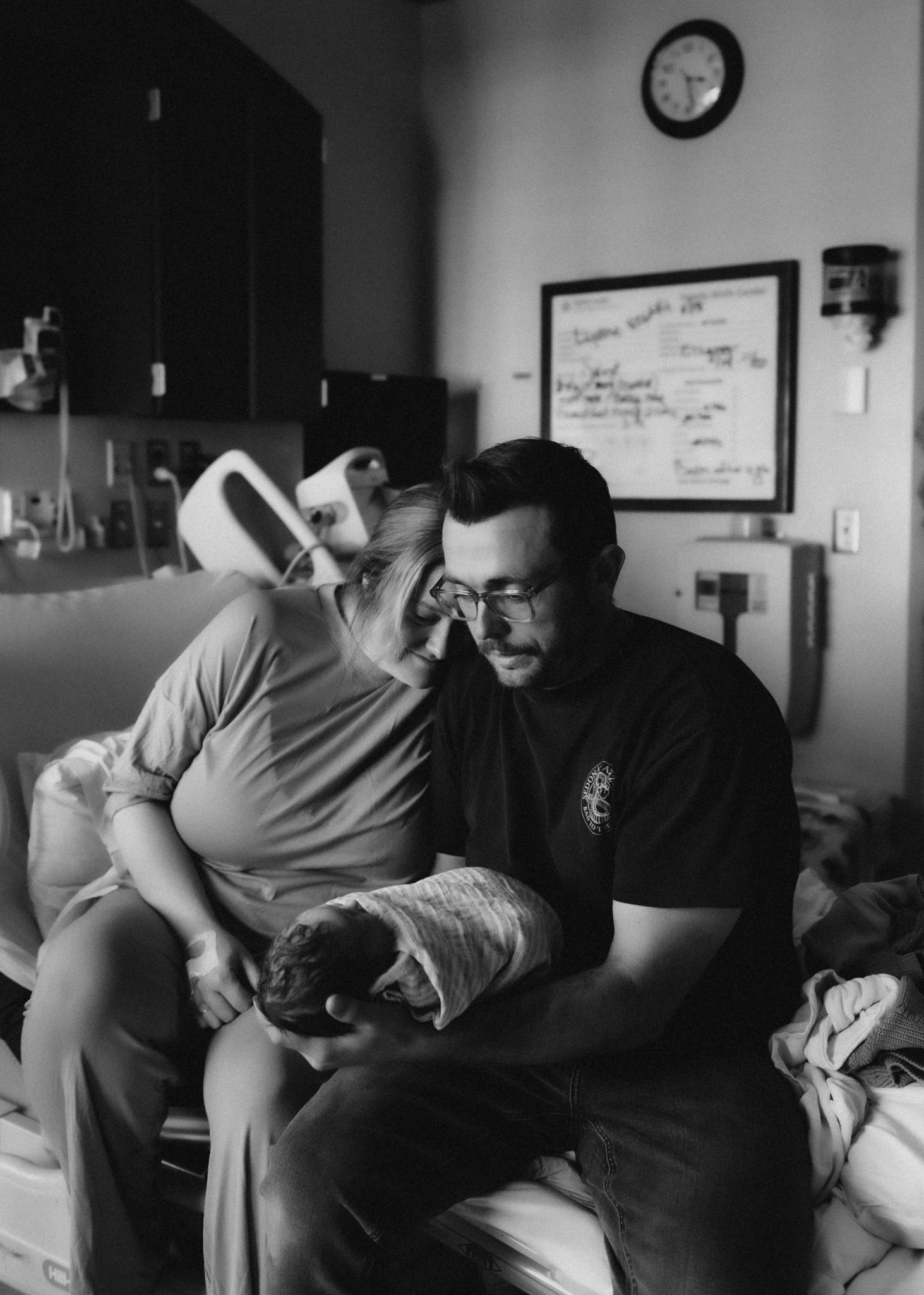 Black and white photo in a medical setting with adults caring for a newborn.