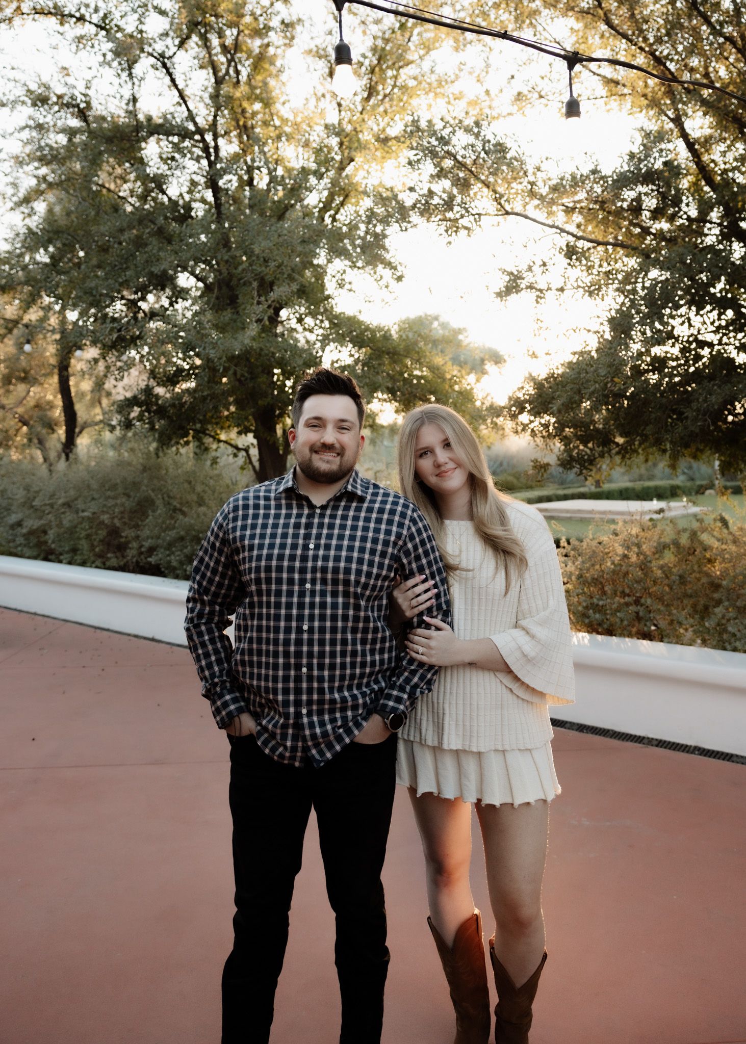 Sunset portrait of couple in casual attire standing on garden path.