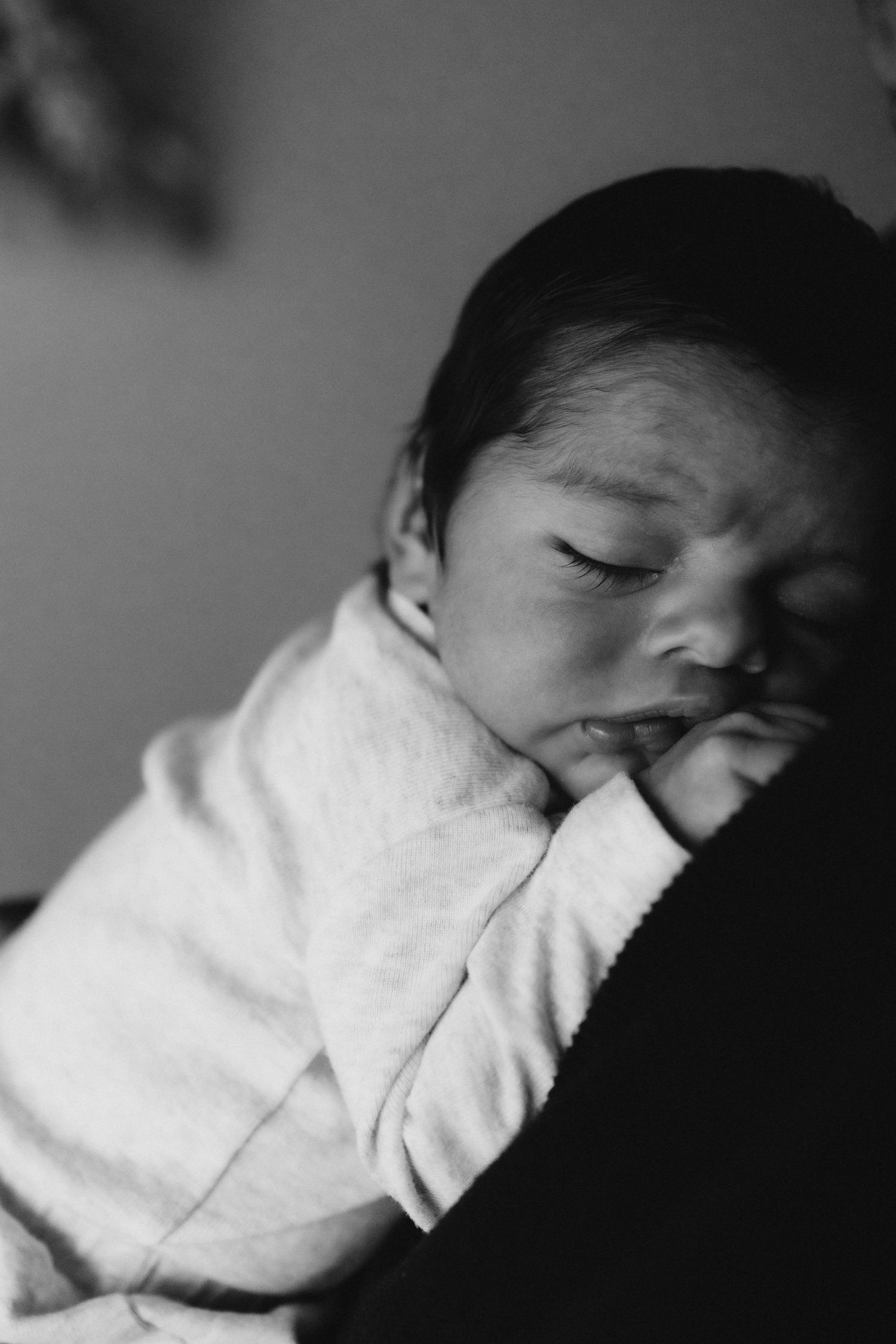 Close-up black and white portrait of sleeping infant in white clothing.