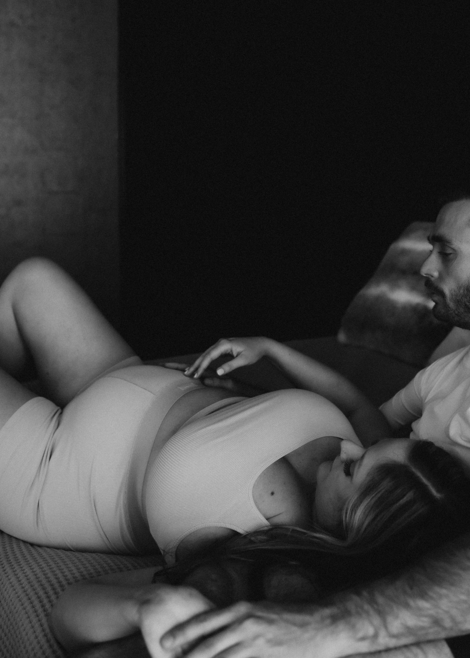 Intimate black and white maternity photo of couple resting together.