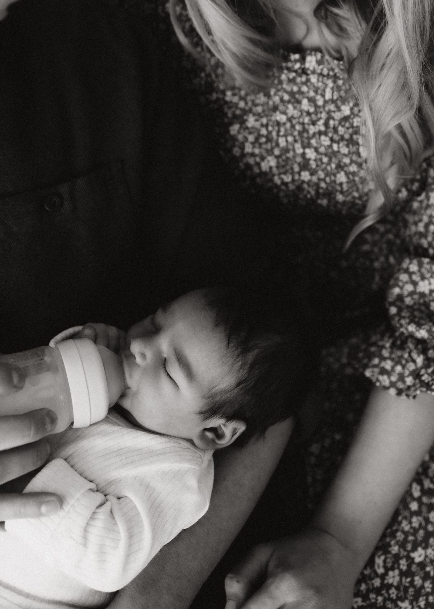 Black and white photo of infant being bottle fed while lying down.