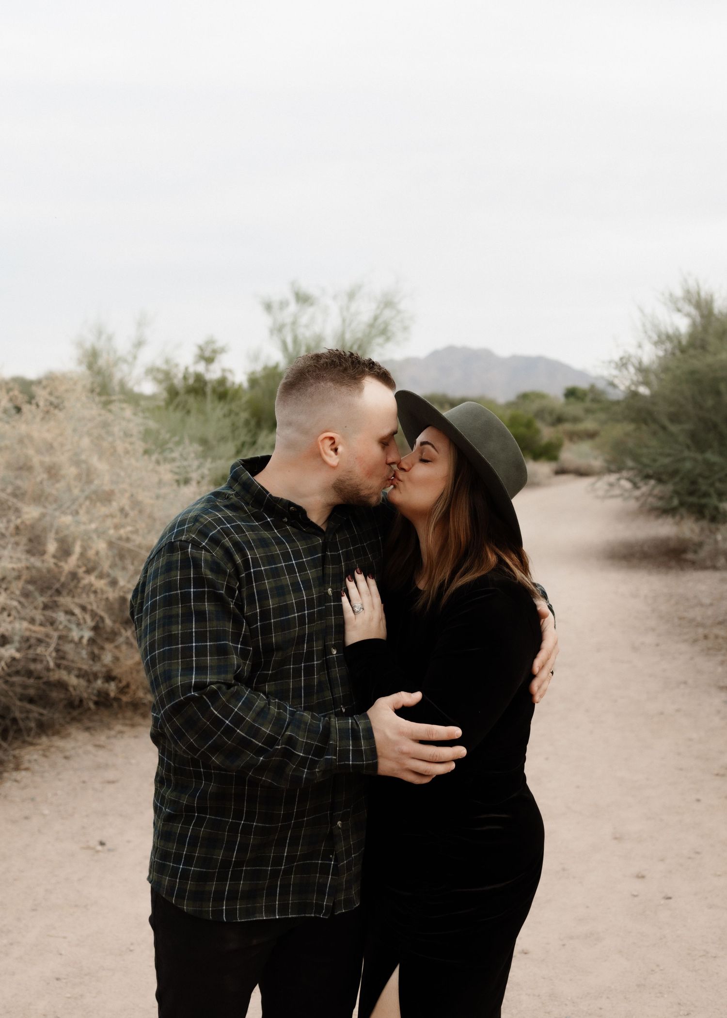 Romantic couple sharing intimate moment on desert path during photo session.