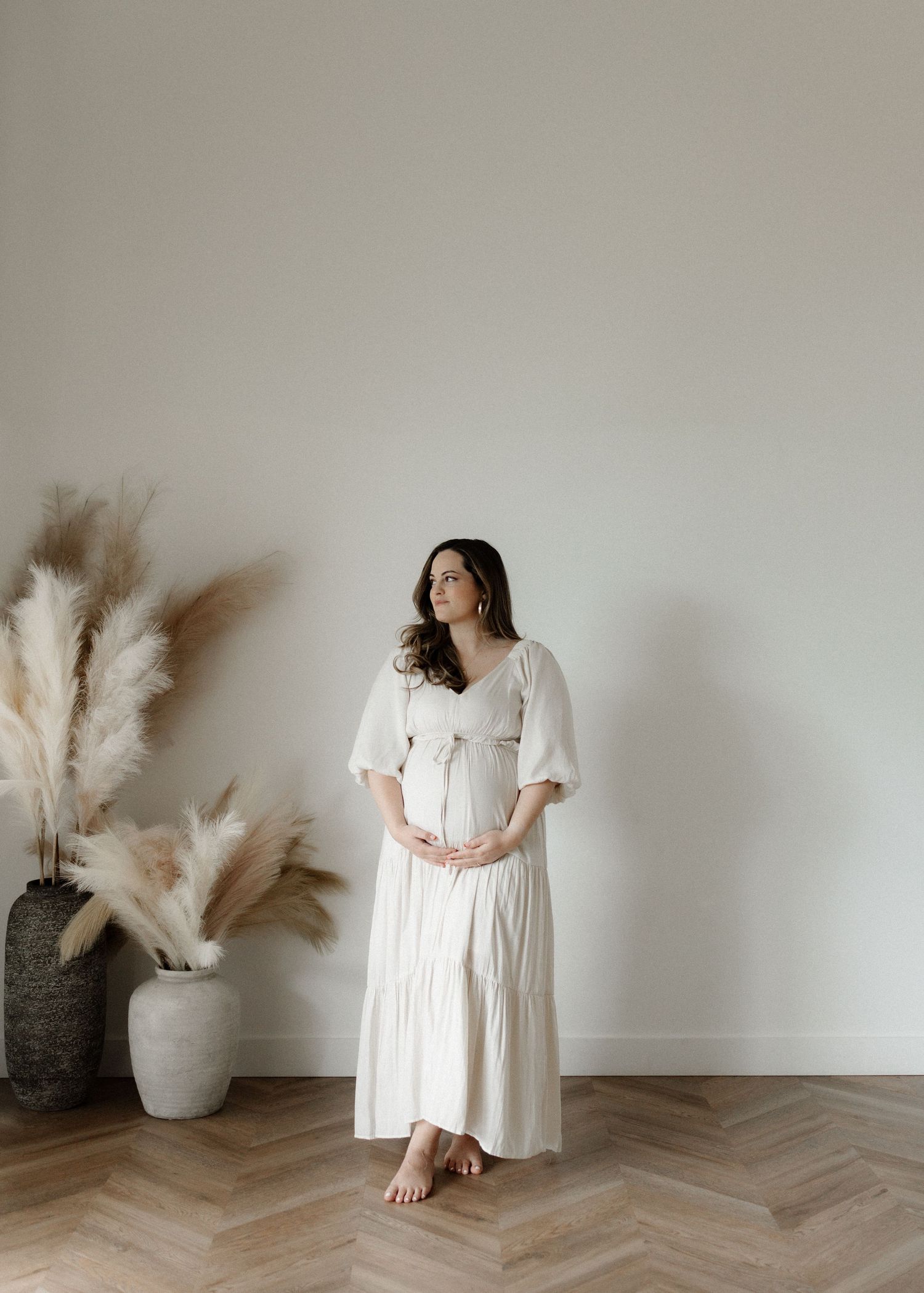 Five minimalist fashion photos show a white midi dress styled against neutral walls with pampas grass decor.