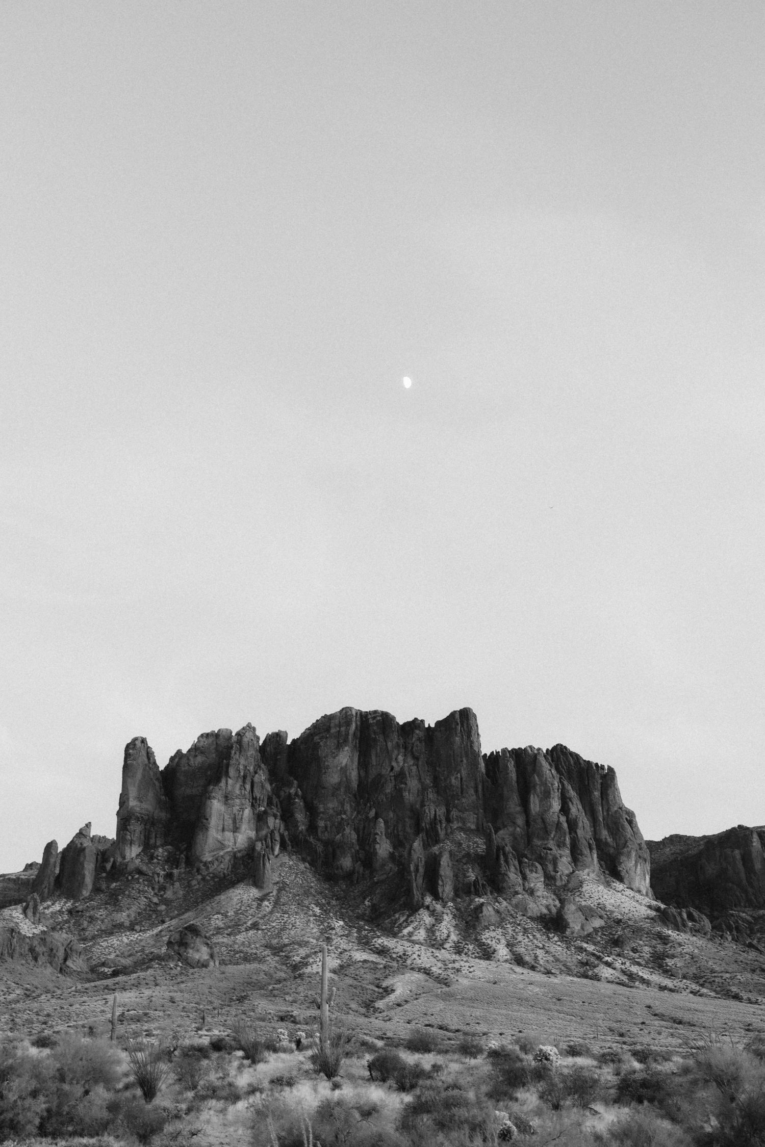 Black and white landscape of rugged mountain cliffs in a desert setting.