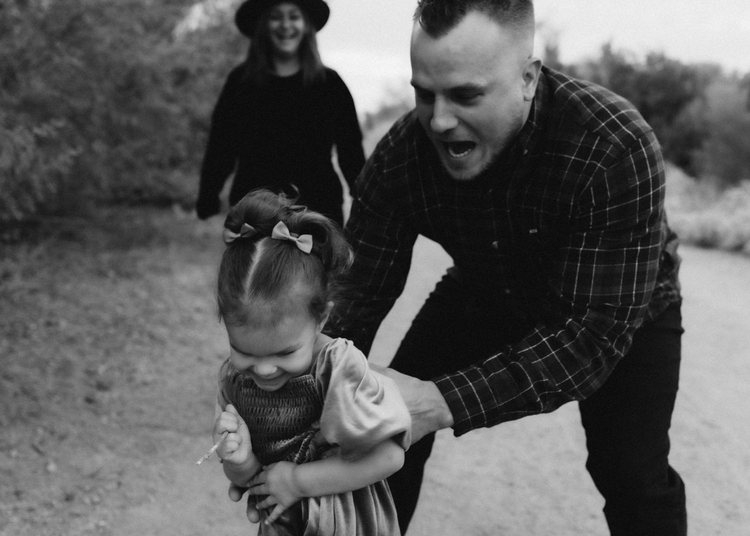 Black and white candid photo of family playing together on desert trail.