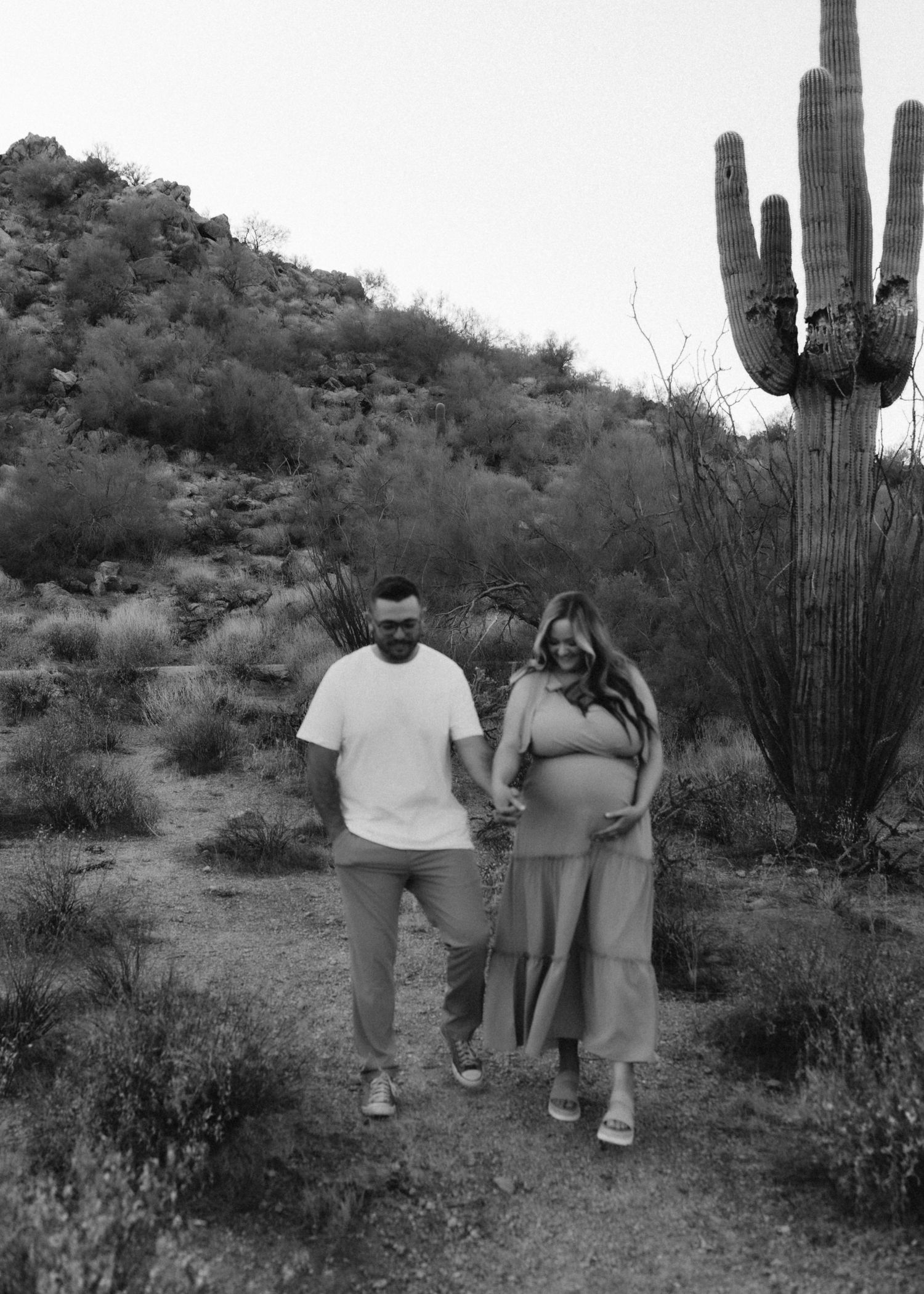 Black and white desert maternity photo with saguaro cactus in background.