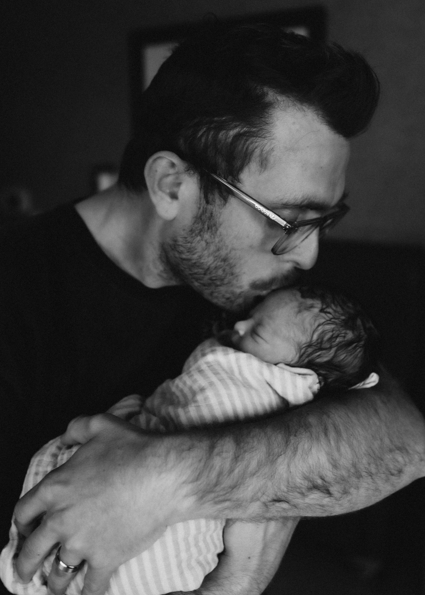 Intimate black and white photo showing parental love while holding a sleeping newborn.
