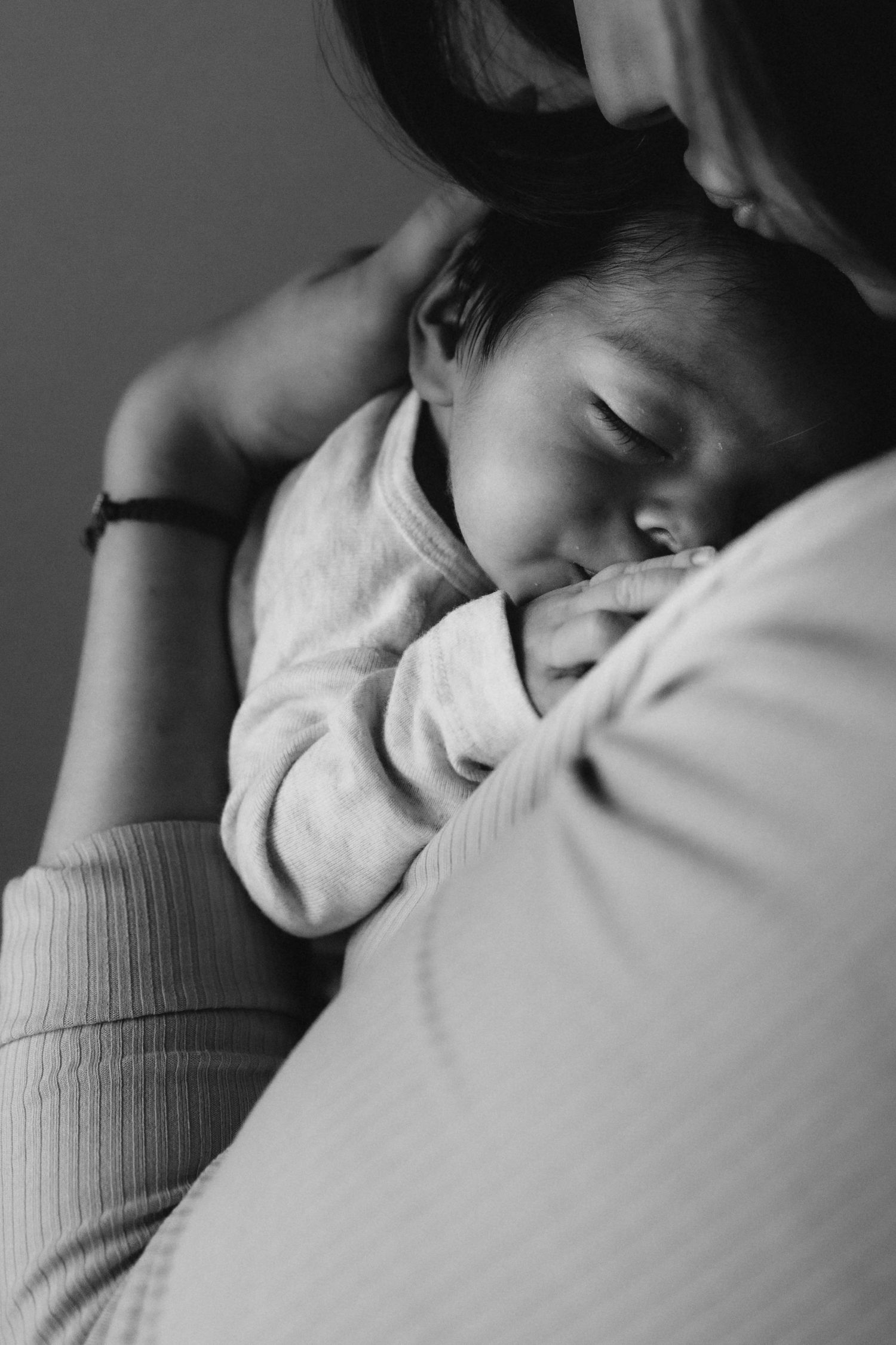 Intimate black and white image of sleeping baby nestled against soft fabric.