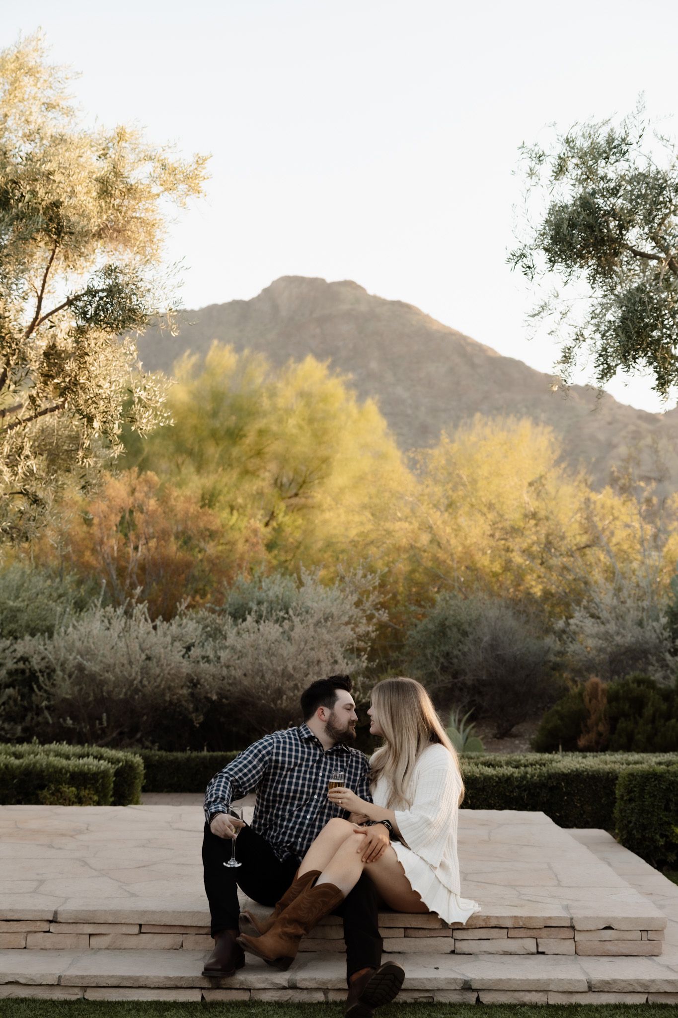 Couple sits on stone steps with scenic mountain view during golden hour.
